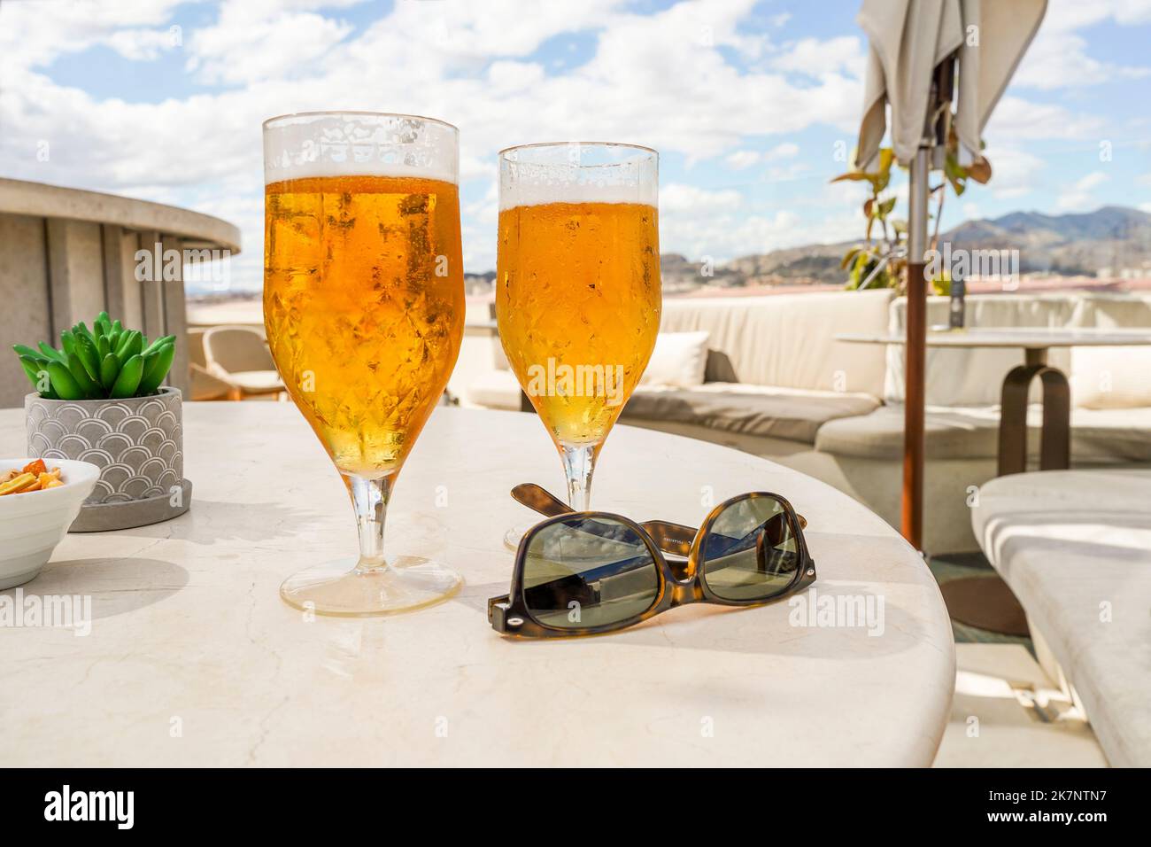 Deux verres avec bière et lunettes de soleil sur une table sur un toit-terrasse, restaurant, Espagne. Banque D'Images