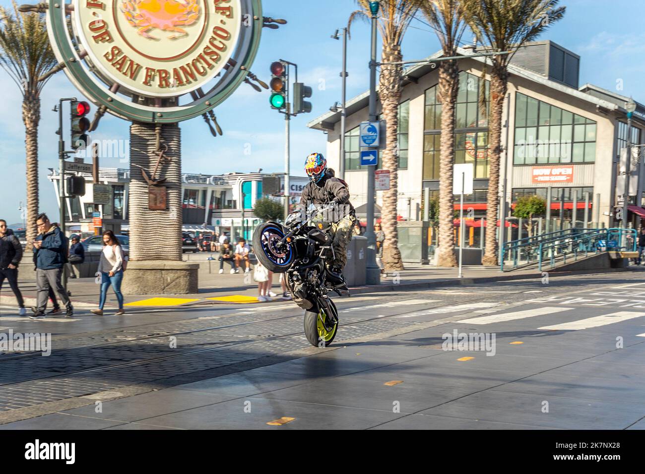 San Francisco, Etats-Unis - 7 juin 2022: Un motard montre un Wheelie à son centre-ville à vélo au quai des pêcheurs. Banque D'Images