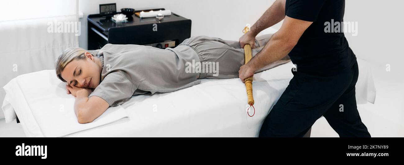 Massage samouraï avec balais en bambou et bâtons pour les jambes et le corps des femmes dans la salle de massage Banque D'Images