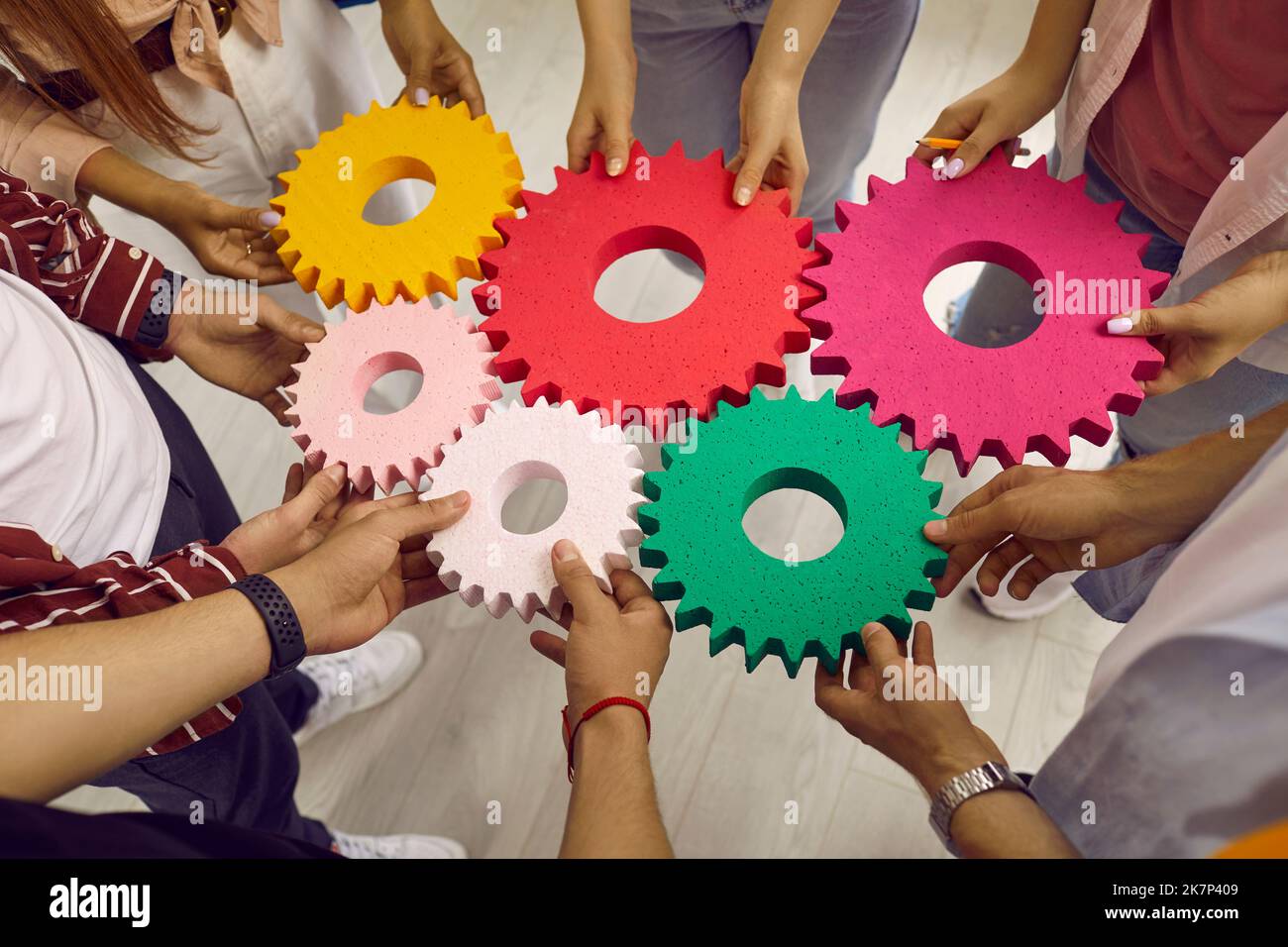Les jeunes créatifs ont des engrenages colorés de différentes tailles, symbolisant un travail d'équipe coordonné. Banque D'Images