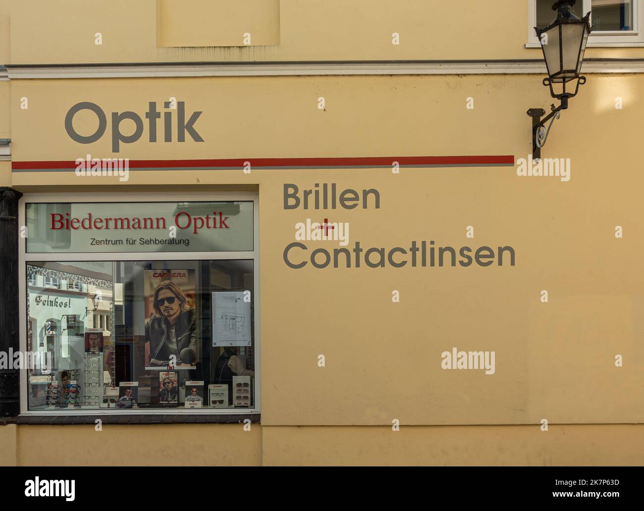 Allemagne, Wismar - 13 juillet 2022: Façade jaune de Biedermann Optik, magasin de détail opticien dans Darkwartstrasse. Objectifs et lunettes présentés derrière Win Banque D'Images