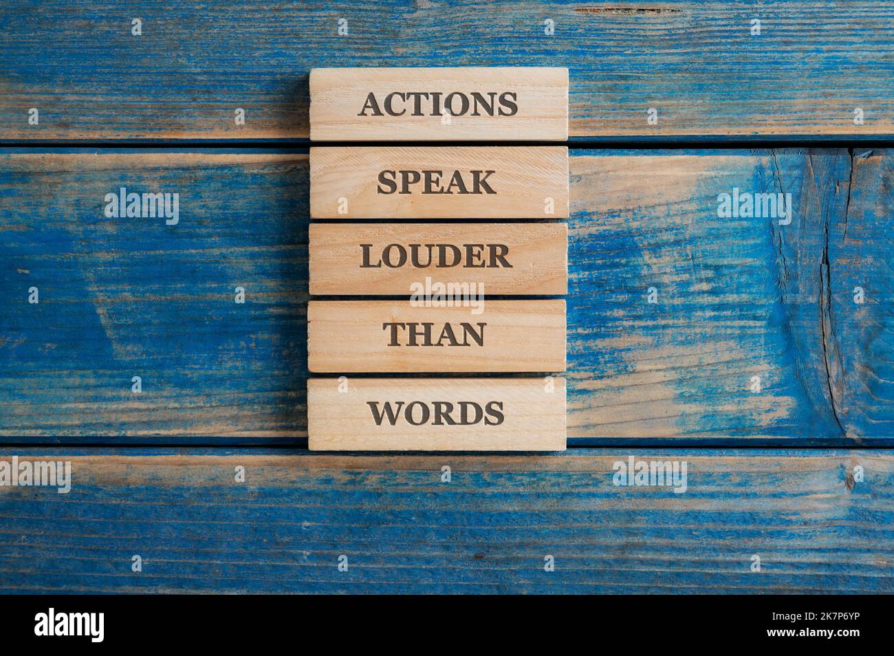 Les actions parlent plus fort que les mots signe écrit sur une pile de cinq chevilles en bois placées sur fond en bois bleu texturé. Banque D'Images