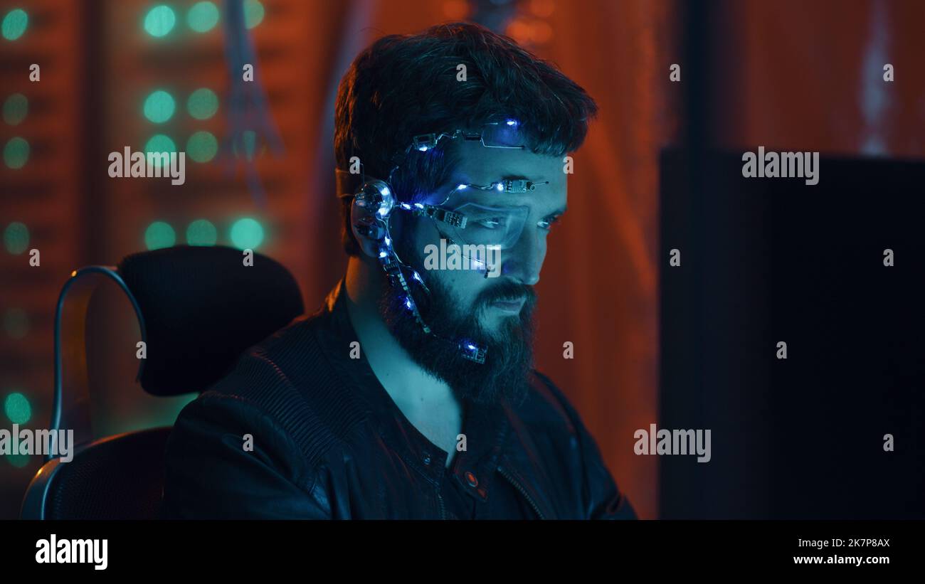 Un Cyberpunk regarde l'écran de l'ordinateur. Port de lunettes futuristes à un œil avec écouteur et microphone. Les arrière-plans de la cyber et de la science-fiction. Banque D'Images