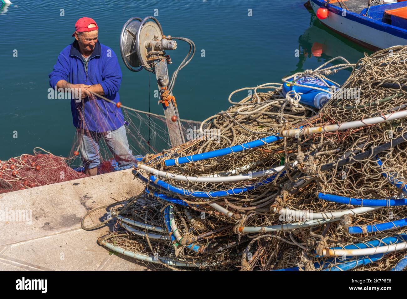 Un pêcheur répare et fixe ses filets après avoir pêché dans la mer Adriatique. Puglia, Italie, Europe Banque D'Images