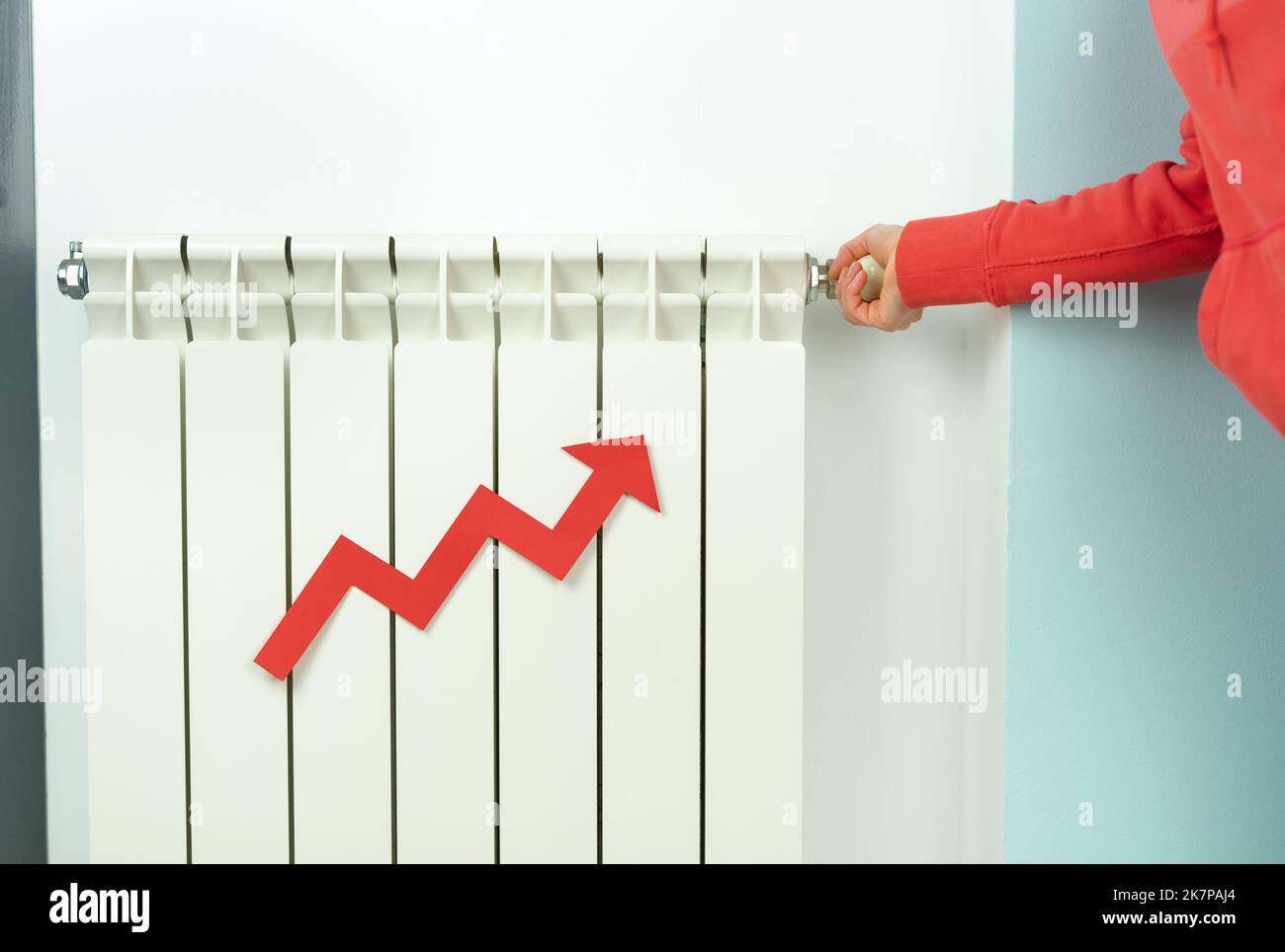 Radiateur de chauffage fermé par la main de femme avec flèche rouge en raison de la hausse des prix de l'électricité. Copier l'espace. Banque D'Images