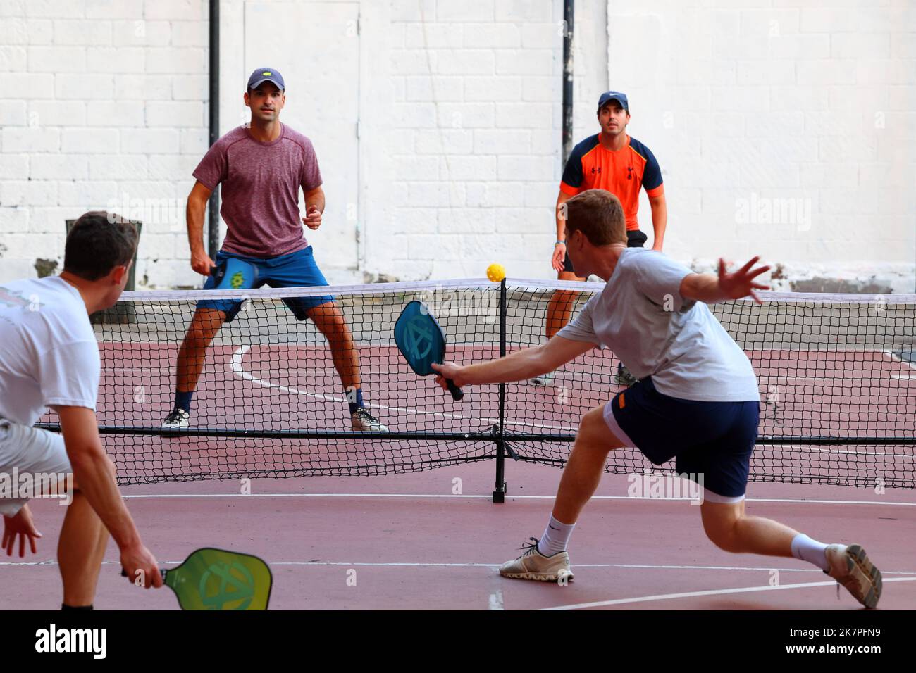 Un groupe de jeunes hommes blancs jouent au pickleball sur un terrain de basket-ball avec double pickleball et striping sur un terrain de basket-ball à Manhattan, New York Banque D'Images