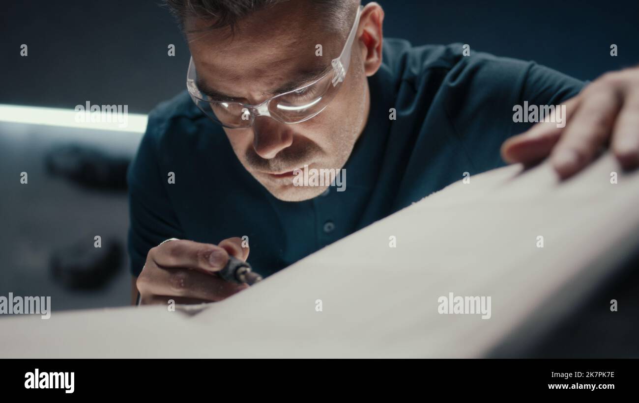 Un concepteur de voiture expérimenté travaille en étroite collaboration sur le modèle de voiture prototype dans une entreprise de fabrication de voiture de haute technologie. Porter des lunettes de sécurité. Il travaille avec une fraiseuse. Banque D'Images