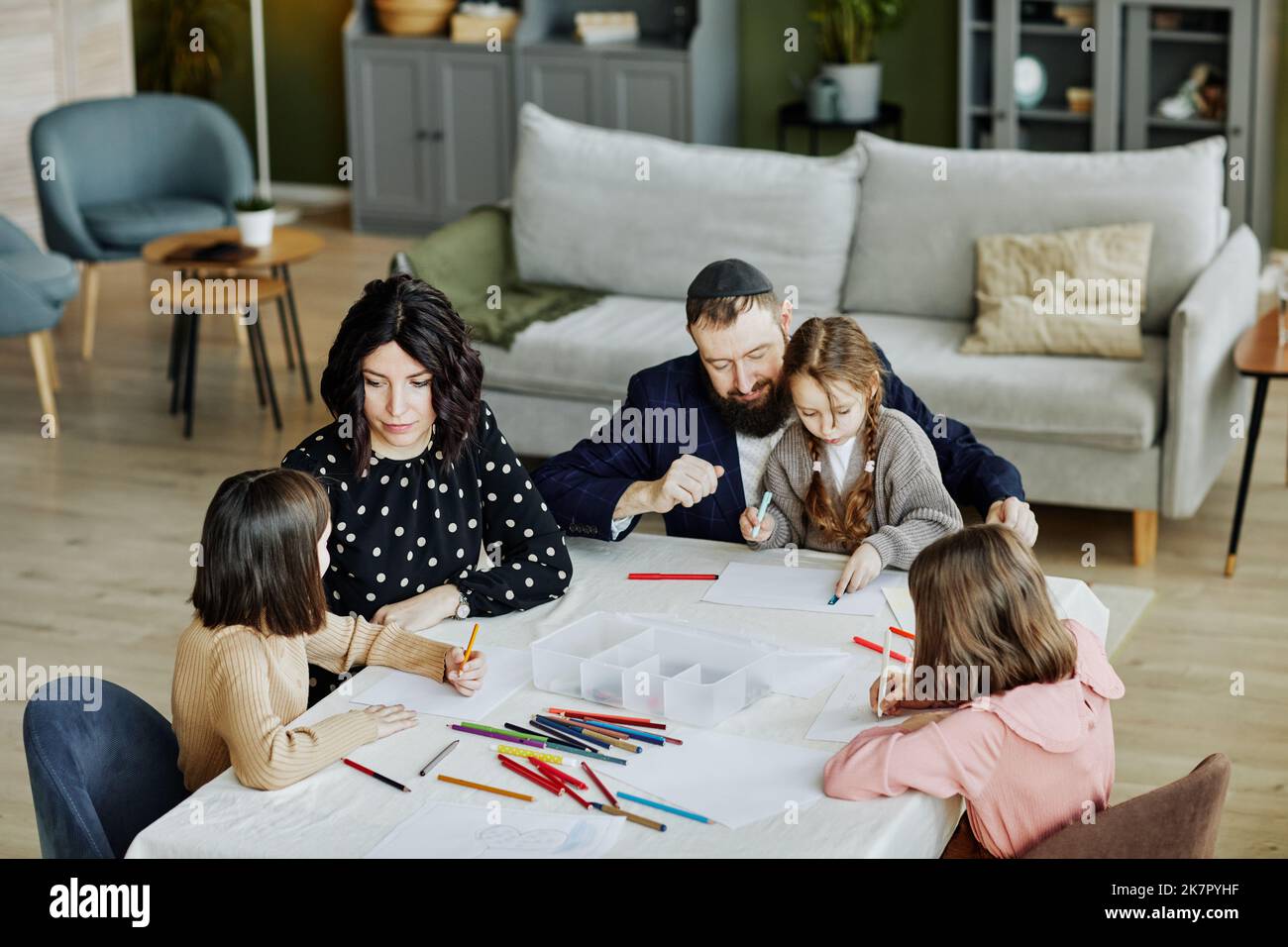 Portrait en grand angle de la famille juive en se dessinant ensemble tout en étant assis à la table à la maison avec trois enfants Banque D'Images