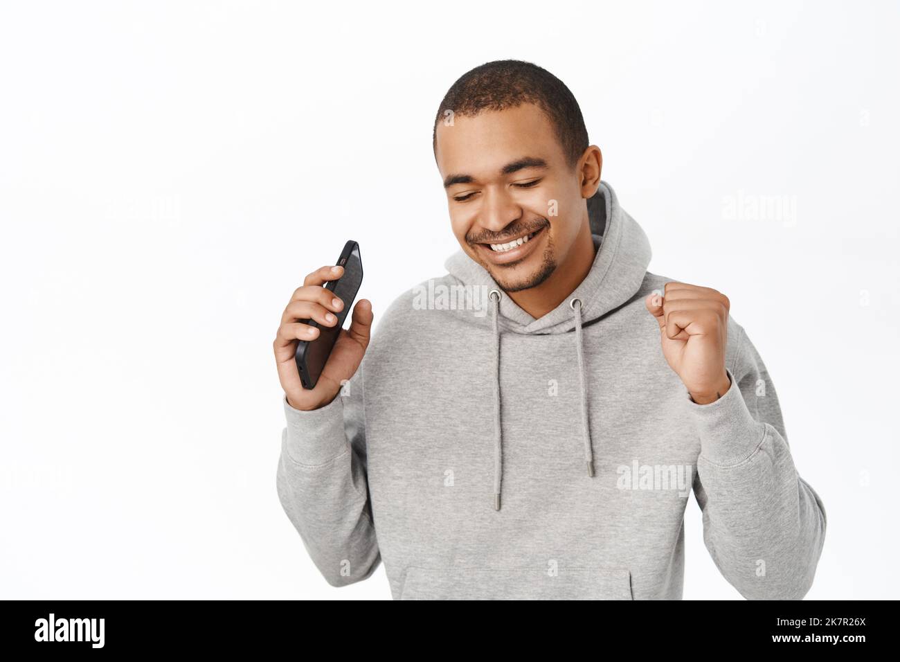Portrait d'un homme heureux écoutant de la musique sur l'application pour smartphone, dansant avec un téléphone portable, debout sur fond blanc Banque D'Images