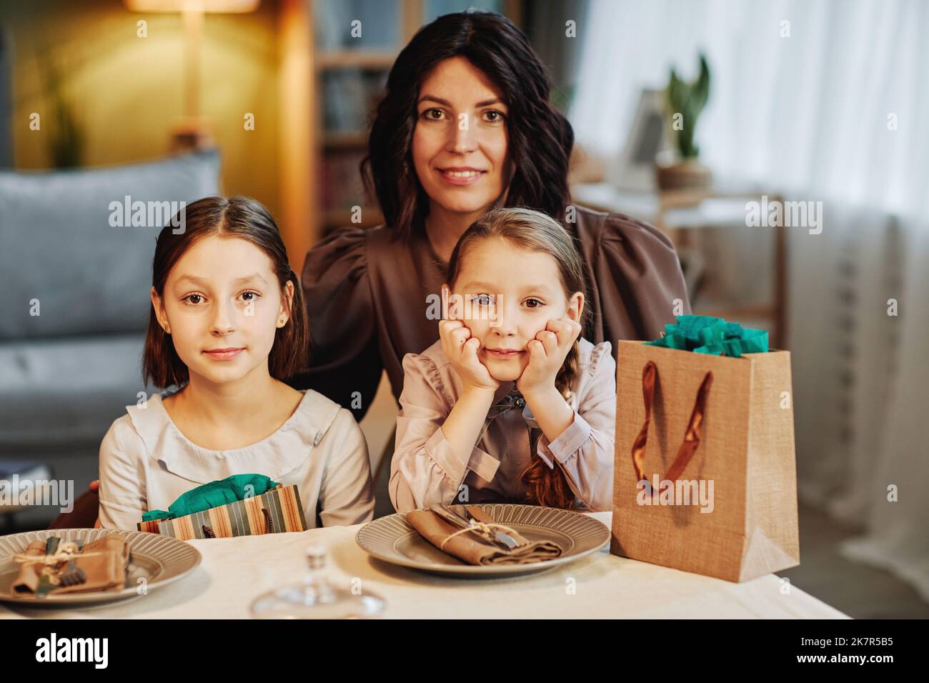 Portrait d'une mère juive moderne avec deux enfants regardant l'appareil photo tout en étant assis à la table du dîner dans un cadre confortable Banque D'Images
