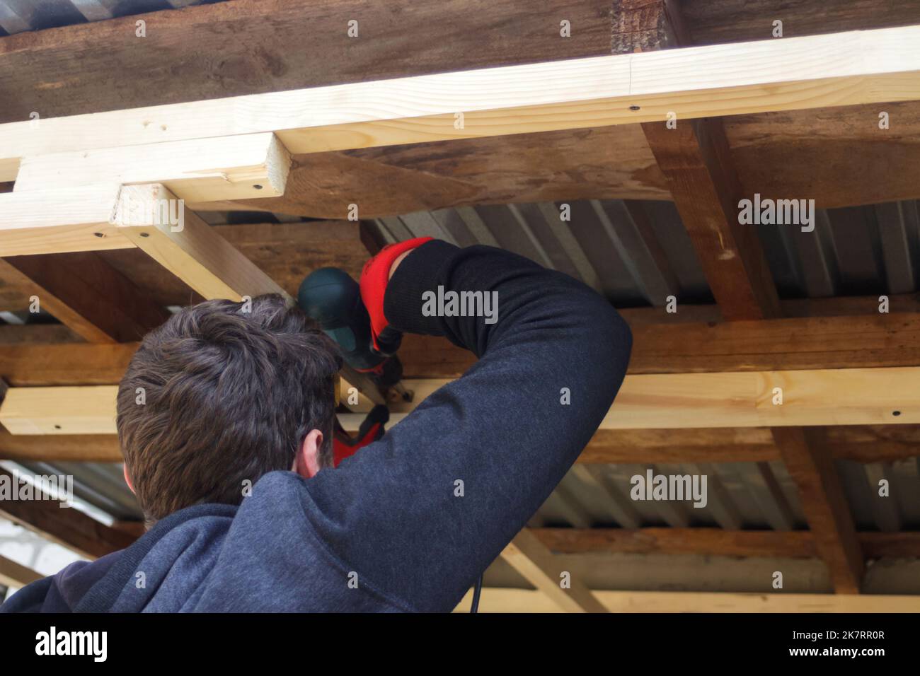 Déconcentrer le travailleur à l'aide d'une perceuse travaillant sur la construction de la maison de cadre en bois et du toit. Des hommes qui fixent une étagère en bois avec son perceuse. Hors foyer Banque D'Images