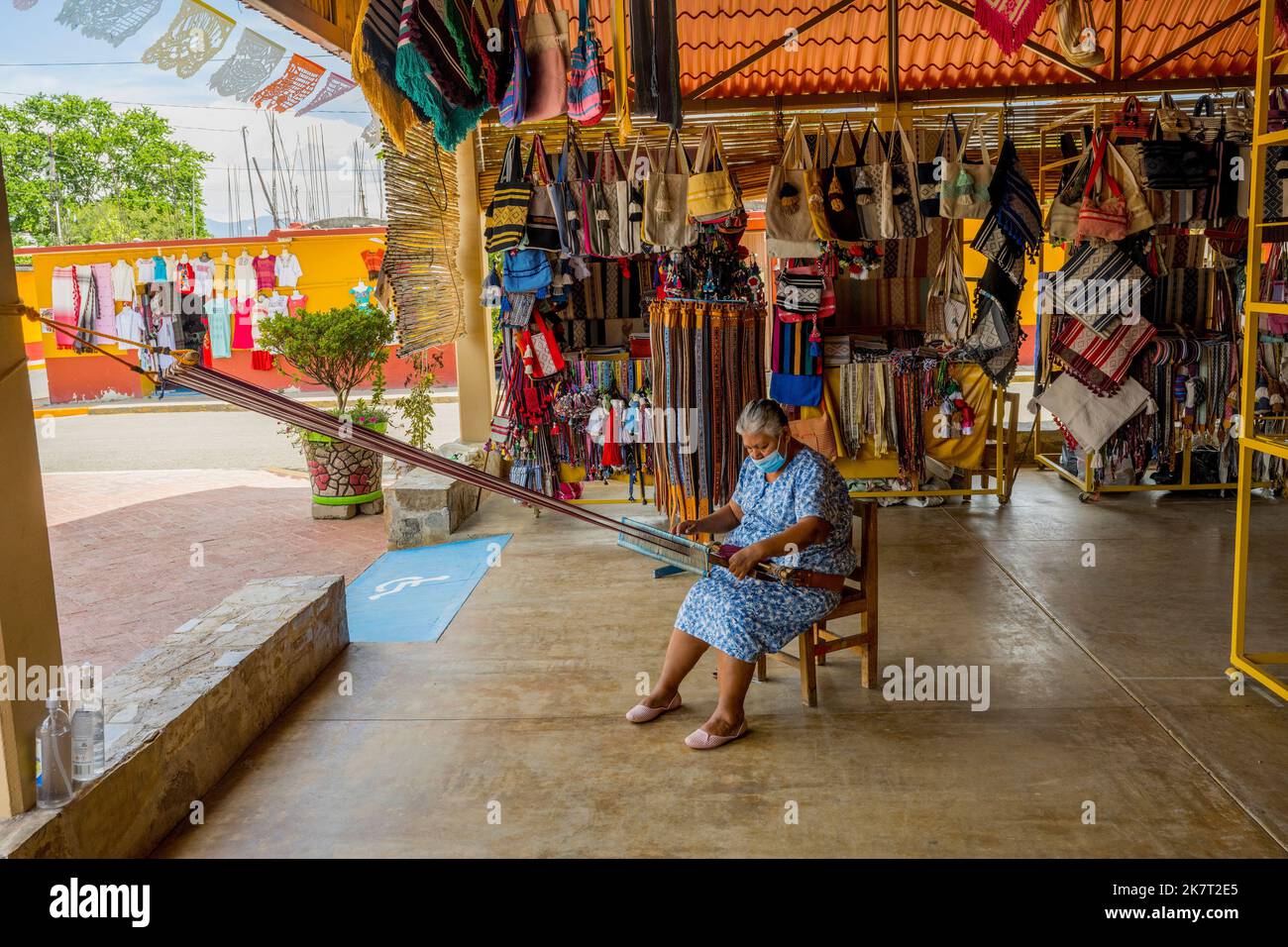 Une femme utilise un métier à tisser à dos pour tisser sur le marché de l'artisanat à Santo Tomas Jalieza près d'Oaxaca, au Mexique. Banque D'Images