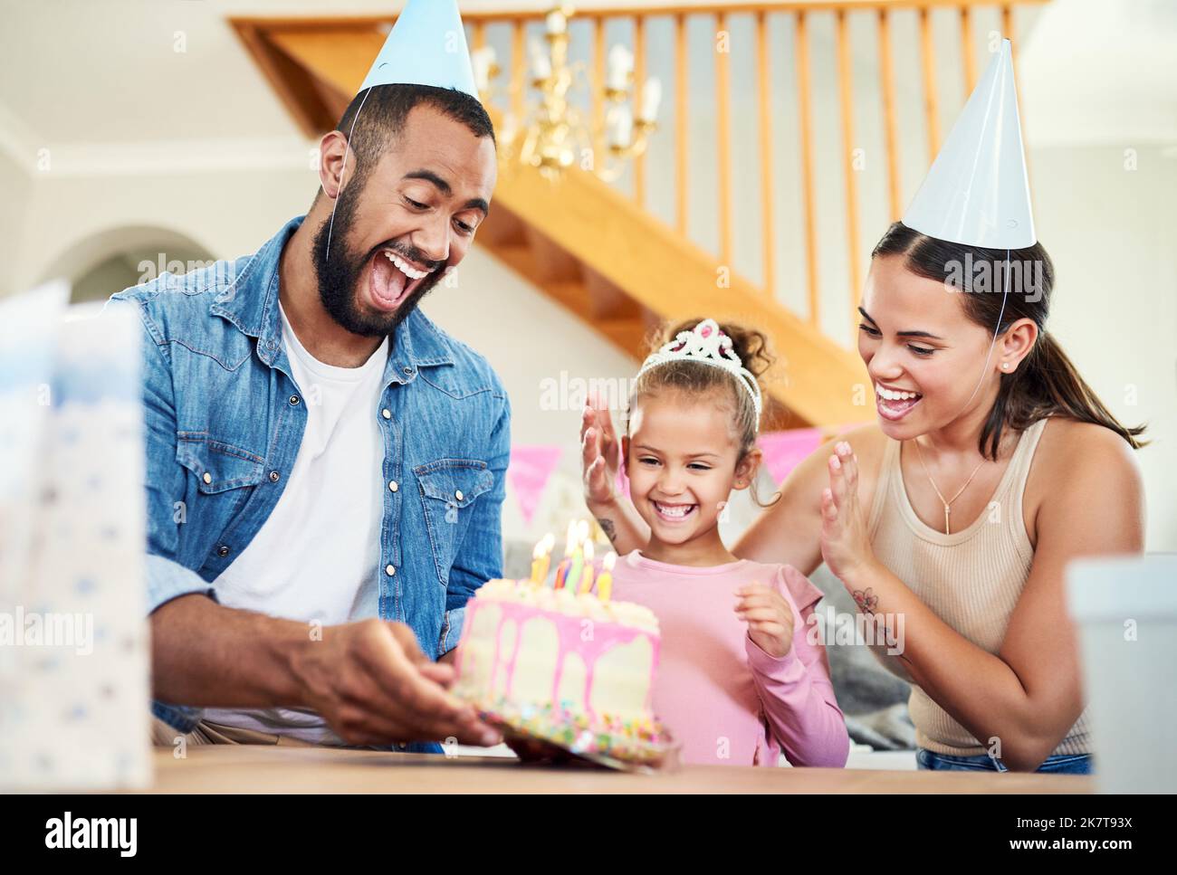 Un gâteau spécial pour une fille spéciale. une petite fille célébrant un anniversaire avec ses parents à la maison. Banque D'Images