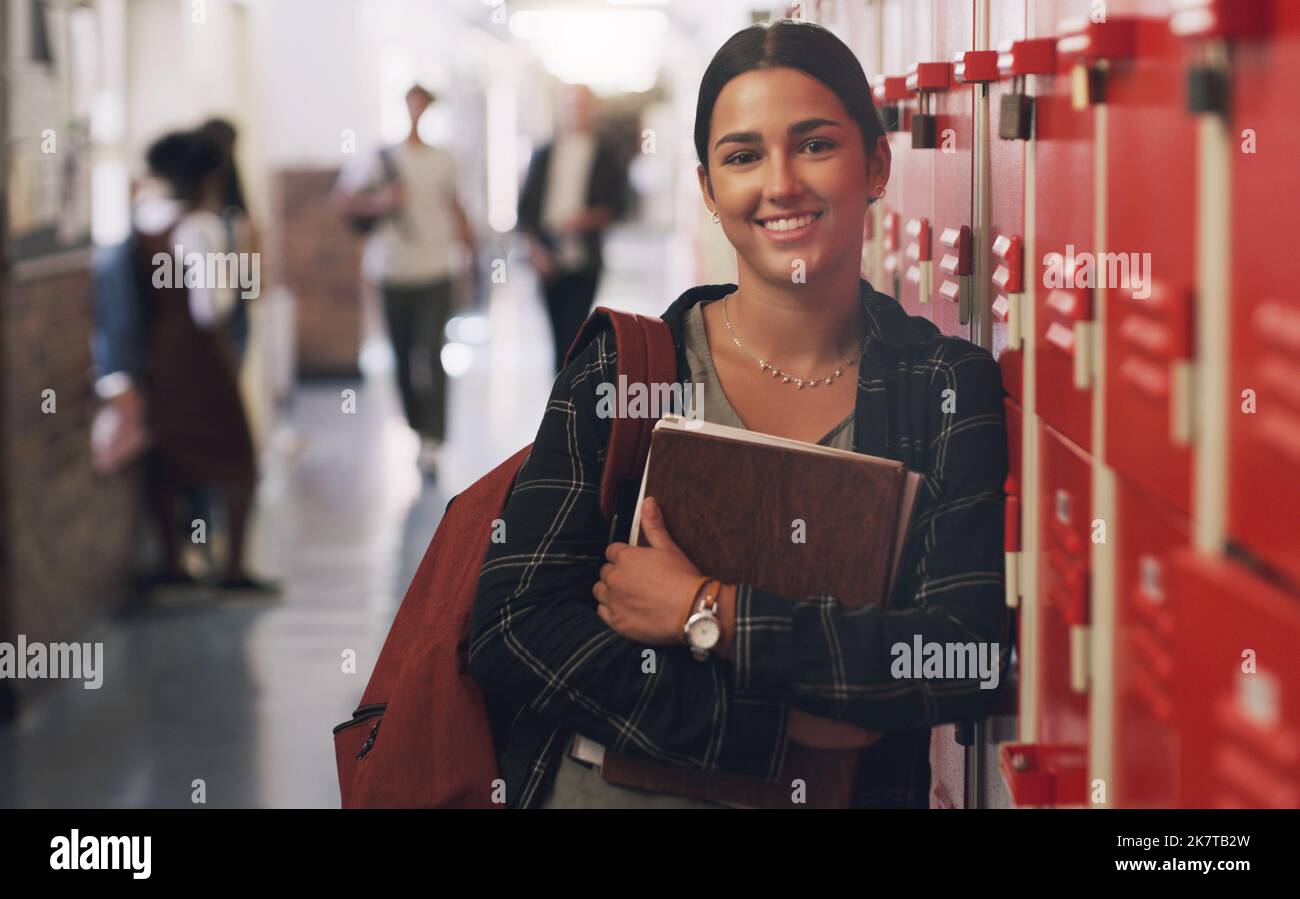 Mon éducation appelle et je dois partir. Portrait d'une adolescente debout à côté de son casier à l'école secondaire. Banque D'Images