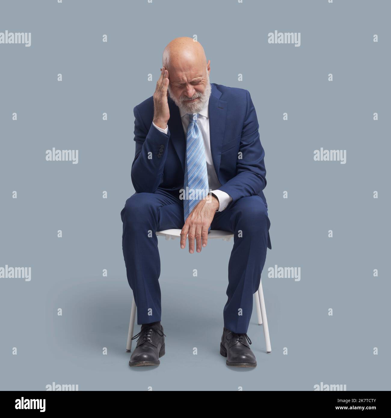 Homme âgé assis sur une chaise, il a un mal de tête Banque D'Images