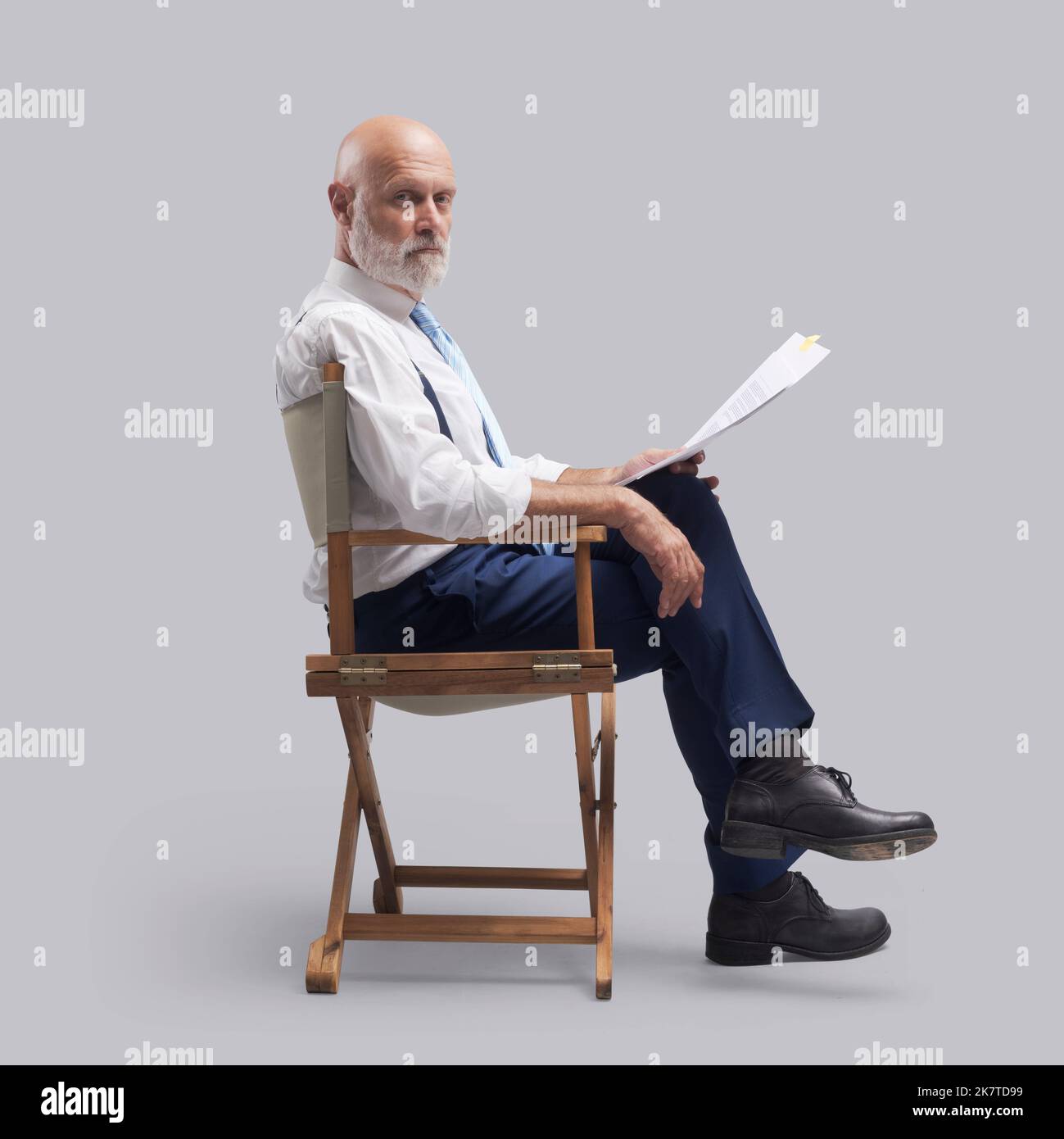 Réalisateur professionnel assis sur la chaise du réalisateur et tenant un scénario, il regarde la caméra Banque D'Images