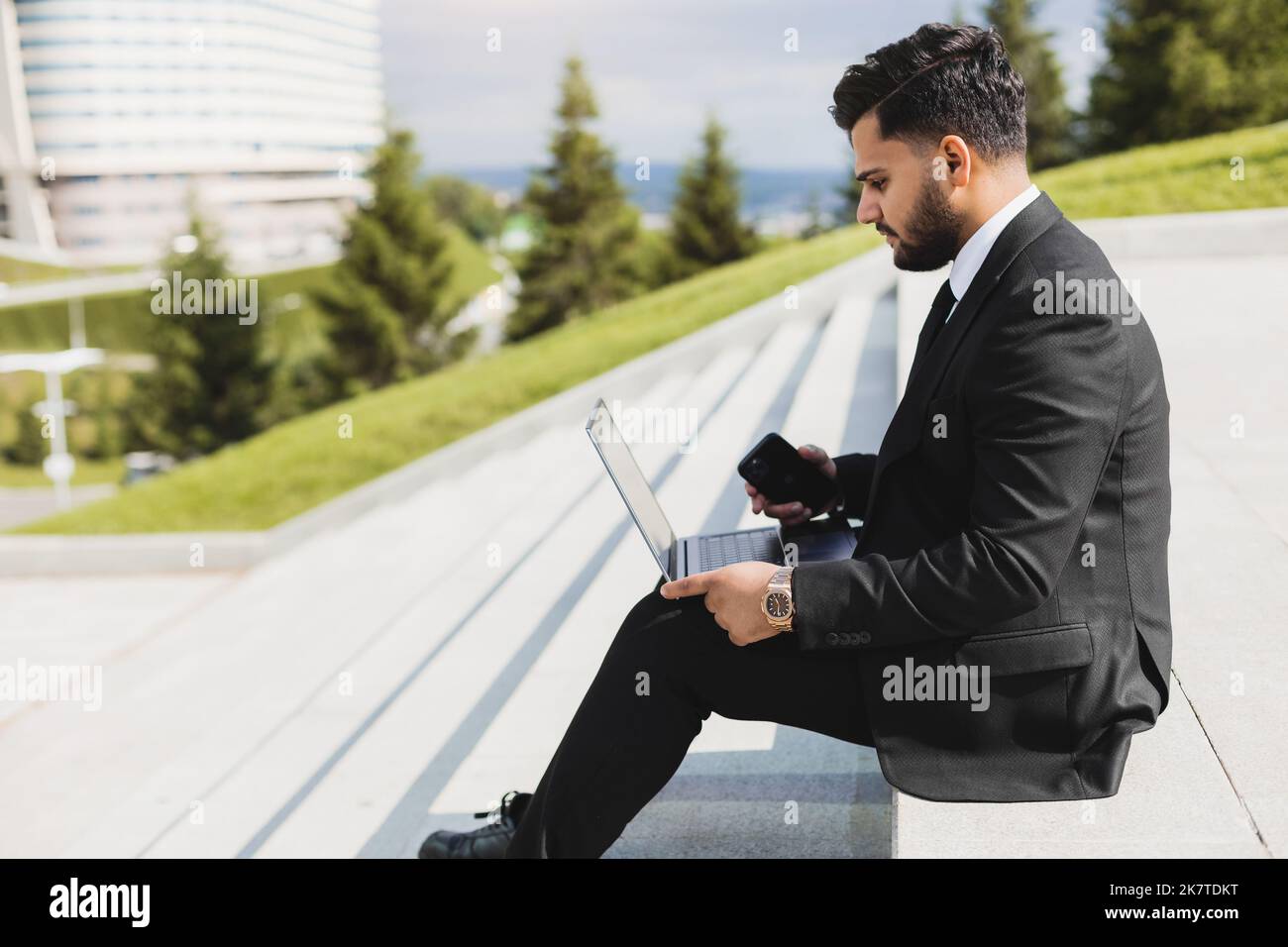Un homme en costume est assis sur les marches d'un escalier de ville avec un ordinateur portable. Pause-travail. Extérieur. Style de vie professionnel Banque D'Images