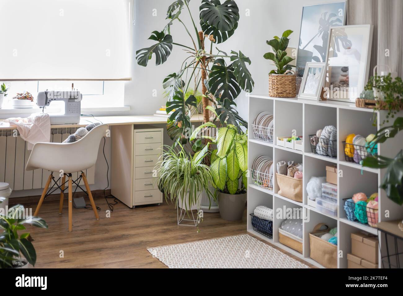 Lieu de travail moderne de la table de designer textile sur mesure avec machine à coudre et ordinateur portable près de la fenêtre Banque D'Images