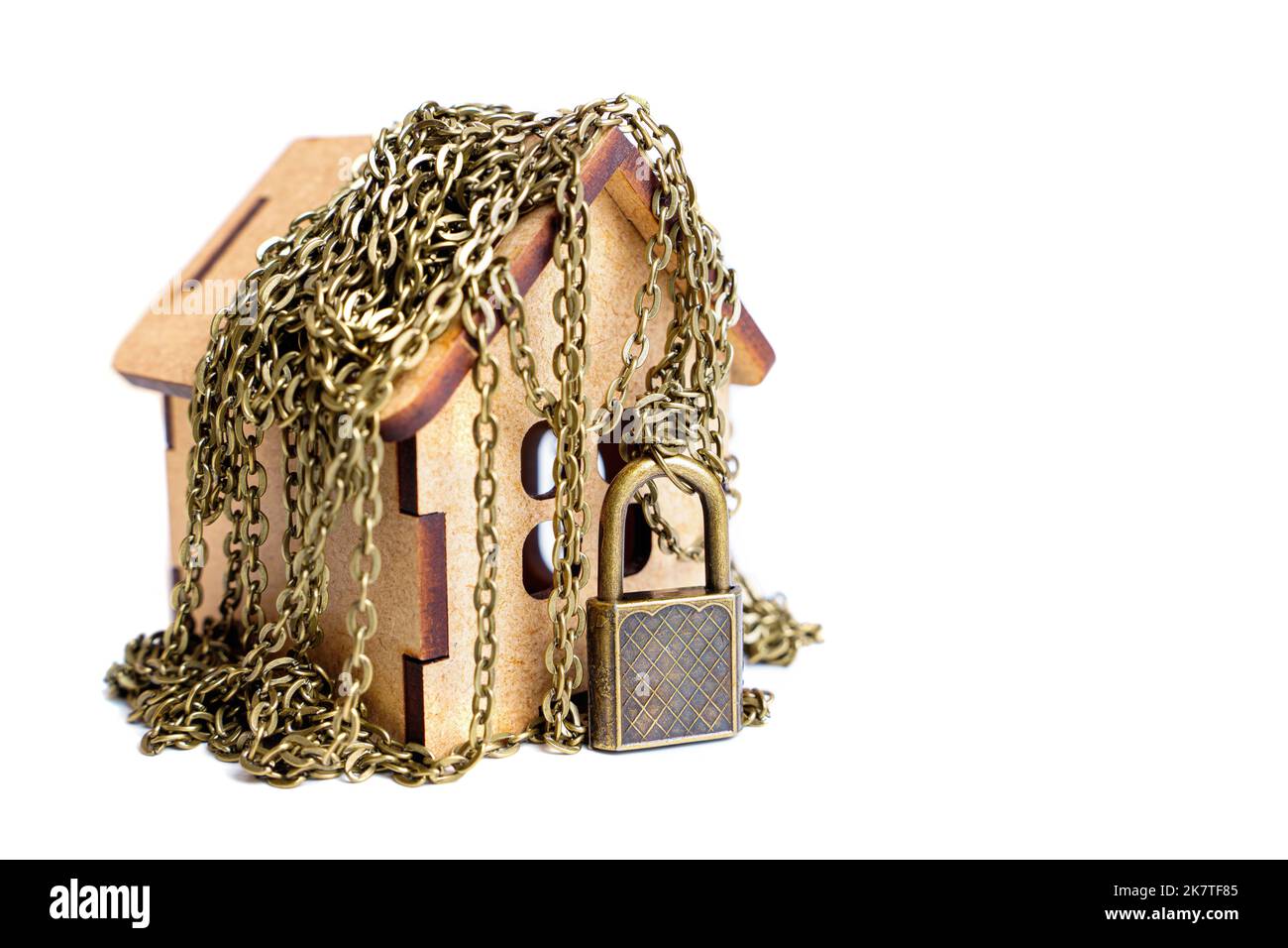 Concept de protection des bâtiments : maison de jouets sécurisée avec des chaînes et un cadenas massif isolé sur fond blanc. Banque D'Images