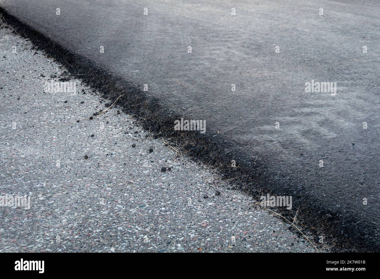 Couches d'asphalte noir frais et gris ancien sur la surface de la route texture diagonale gros plan. Banque D'Images