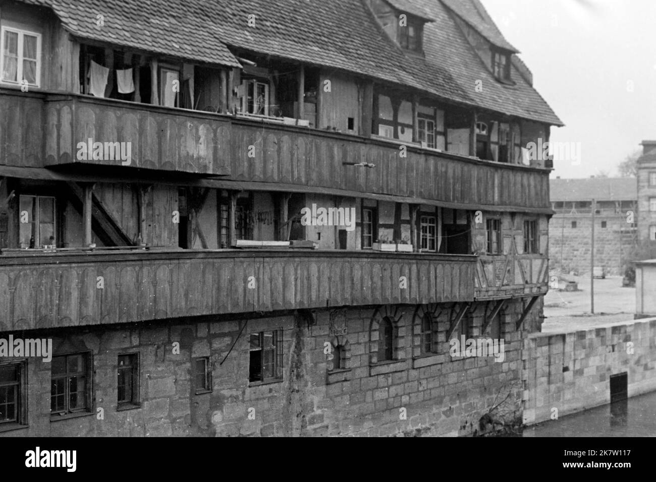 Traditionelles Wohngebäude mit Holzbalkons an der Pegnitz, Nürnberg 1957. Bâtiment résidentiel traditionnel avec balcons en bois sur la rive de la rivière Pegnitz, Nuremberg vers 1957. Banque D'Images