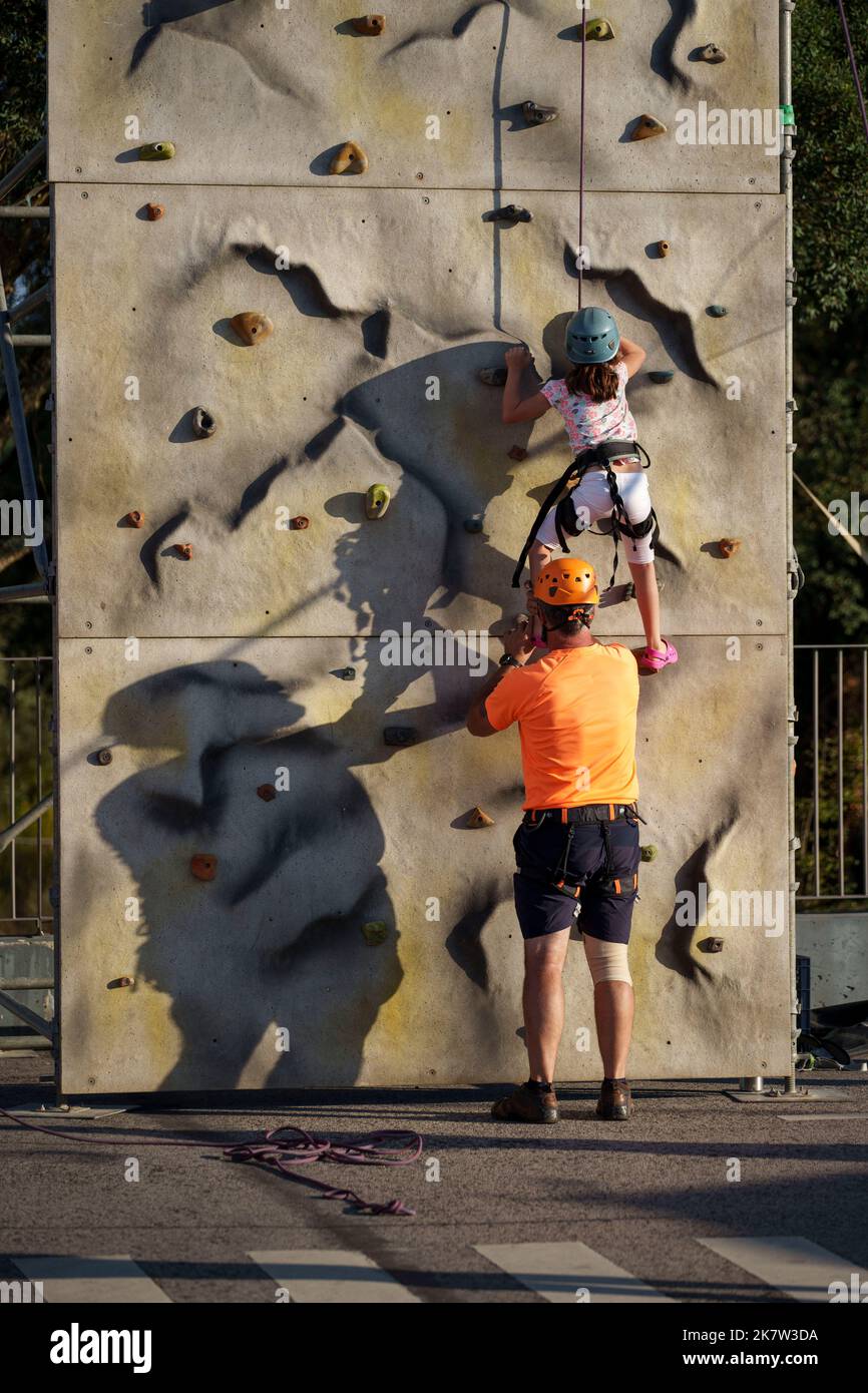 Adulte aidant une jeune fille ont du plaisir sur un mur d'escalade extérieur Banque D'Images