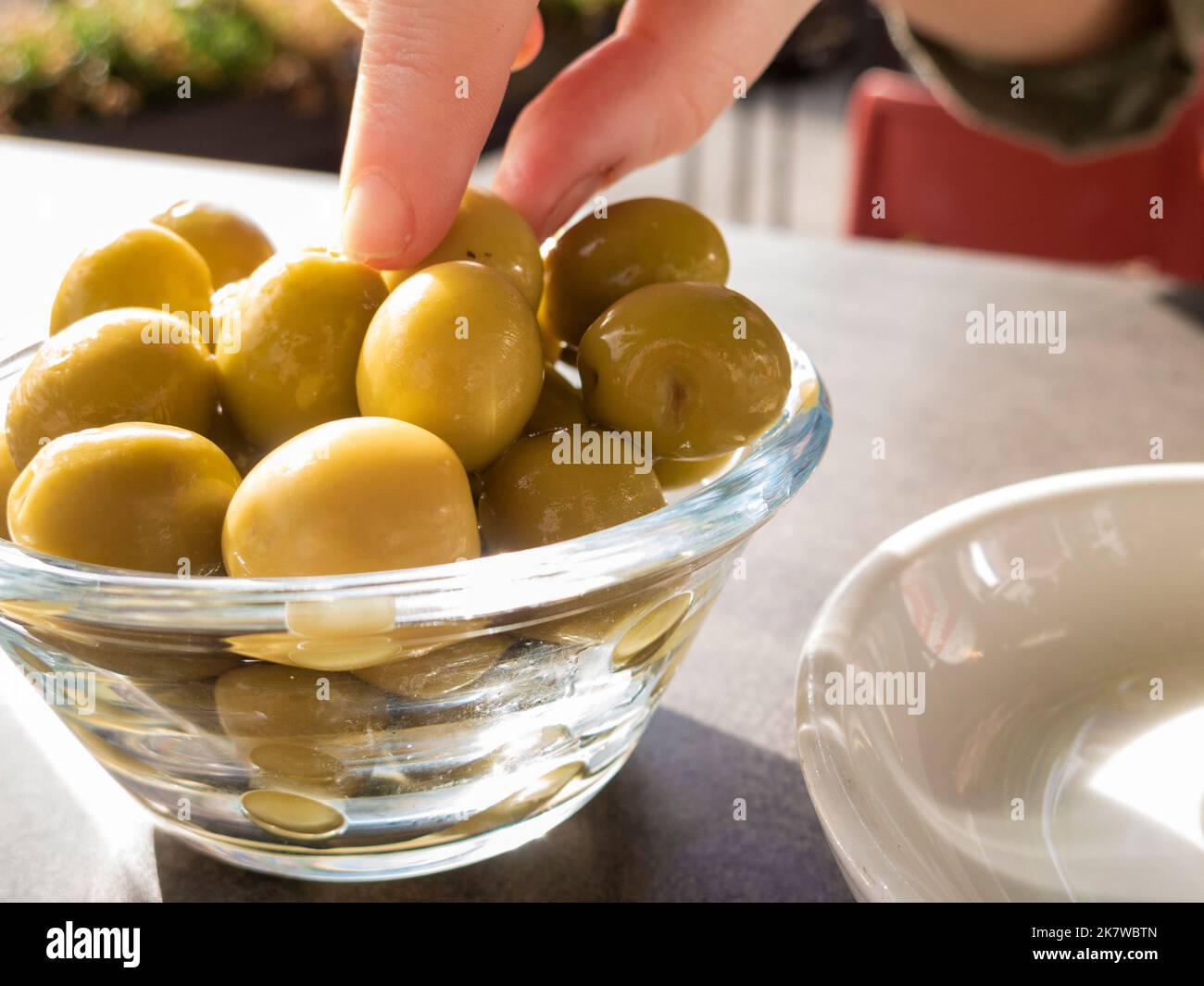 main de femme prenant une olive d'un bol sur la terrasse d'un bar Banque D'Images
