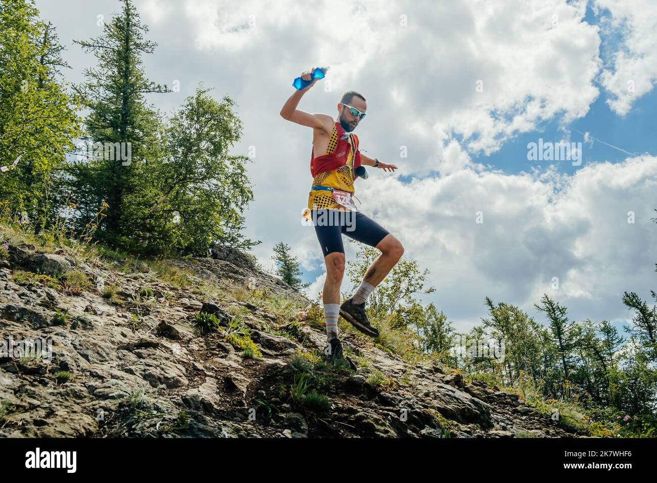 Bannoe, Russie - 31 juillet 2022 : un coureur de sexe masculin part en descente de montagne abrupte sur le sentier sauvage de MMK Banque D'Images Bannoe, Russie - 31 juillet 2022 : un coureur de sexe masculin part en descente de montagne abrupte sur le sentier sauvage de MMK Banque D'Images