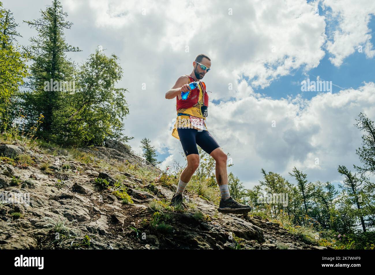 Bannoe, Russie - 31 juillet 2022 : un coureur de sexe masculin part en descente de montagne abrupte sur le sentier sauvage de MMK Banque D'Images Bannoe, Russie - 31 juillet 2022 : un coureur de sexe masculin part en descente de montagne abrupte sur le sentier sauvage de MMK Banque D'Images