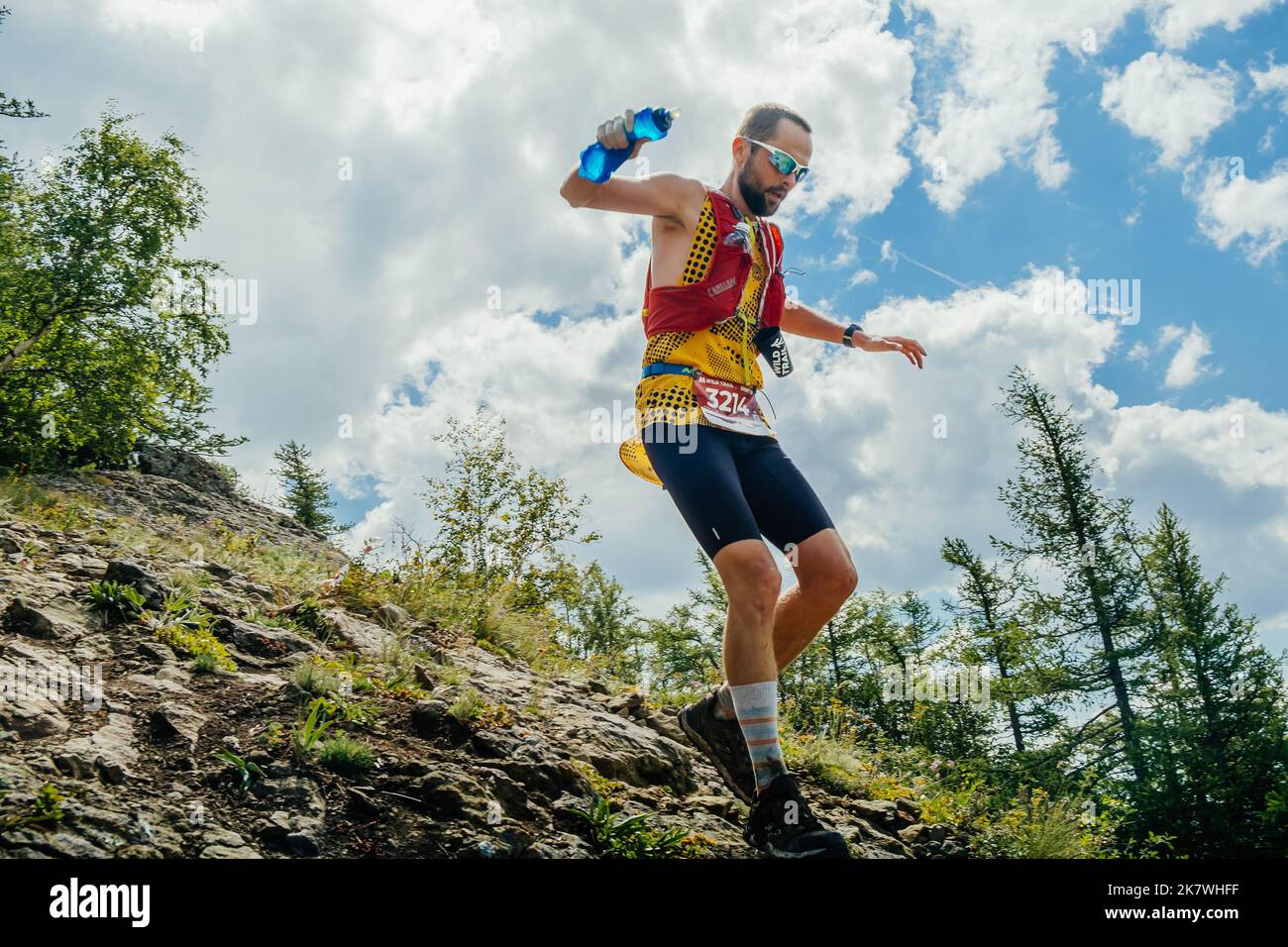 Bannoe, Russie - 31 juillet 2022 : un coureur de sexe masculin part en descente de montagne abrupte sur le sentier sauvage de MMK Banque D'Images Bannoe, Russie - 31 juillet 2022 : un coureur de sexe masculin part en descente de montagne abrupte sur le sentier sauvage de MMK Banque D'Images