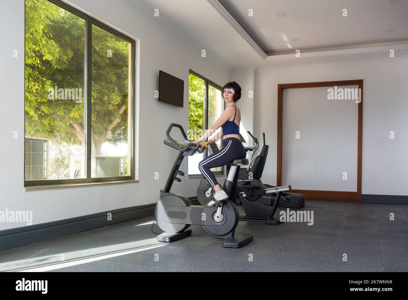 Une femme de 40-44 ans est engagée dans une salle de sport sur un vélo d'exercice. Banque D'Images