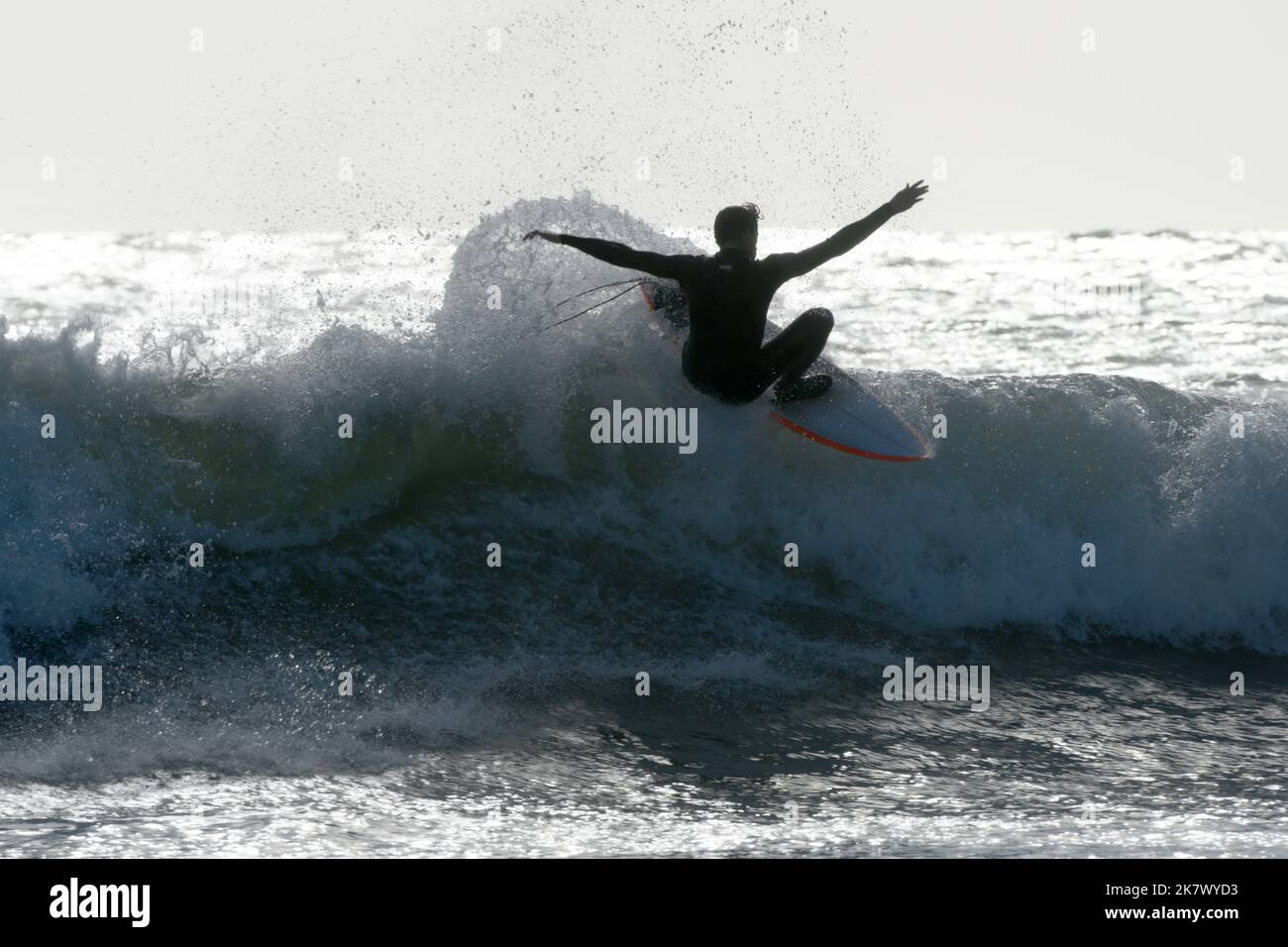 Surf sur Gower, pays de Galles. Un surfeur est silhoueté contre la mer ensoleillée Banque D'Images