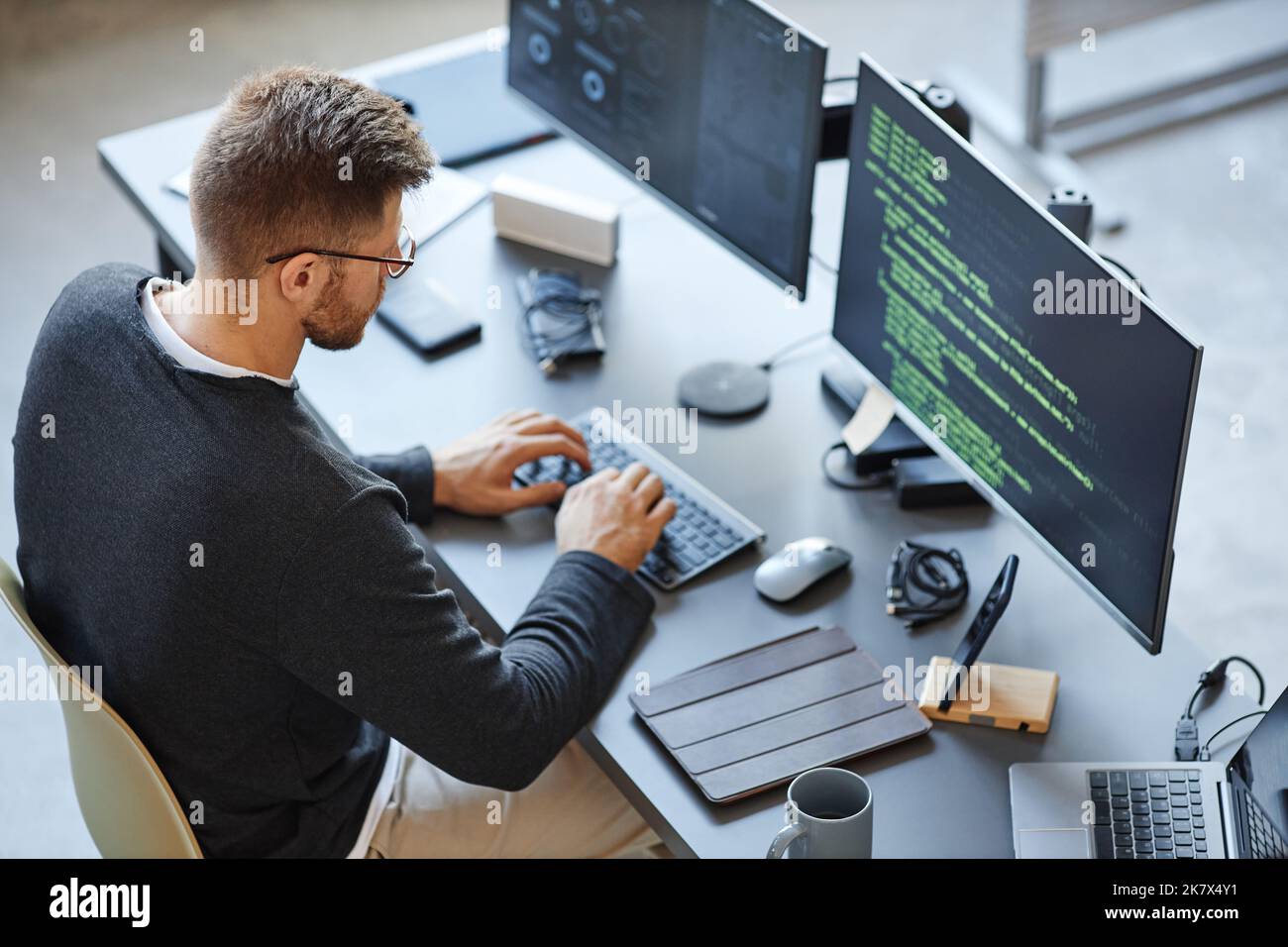 Vue en grand angle chez les développeurs de logiciels qui écrivent du code tout en utilisant des ordinateurs et des systèmes de données au bureau Banque D'Images