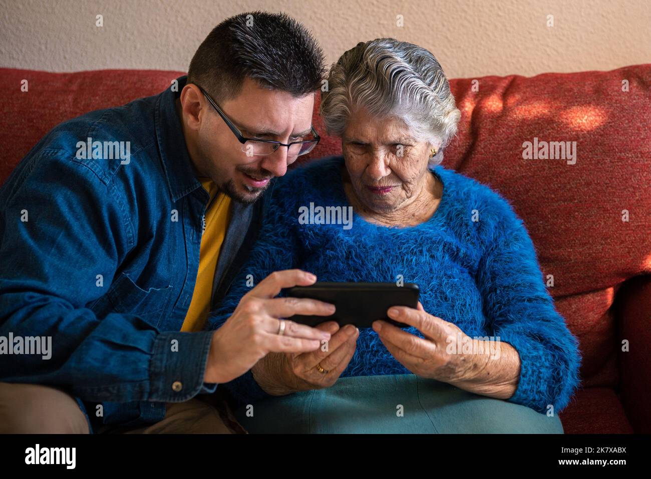 Bonne joyeuse femme de grand-mère âgée qui parle à la famille lors d'un appel de vidéo conférence, parlant à des petits-enfants en ligne sur un canapé à la maison. Relation familiale Banque D'Images