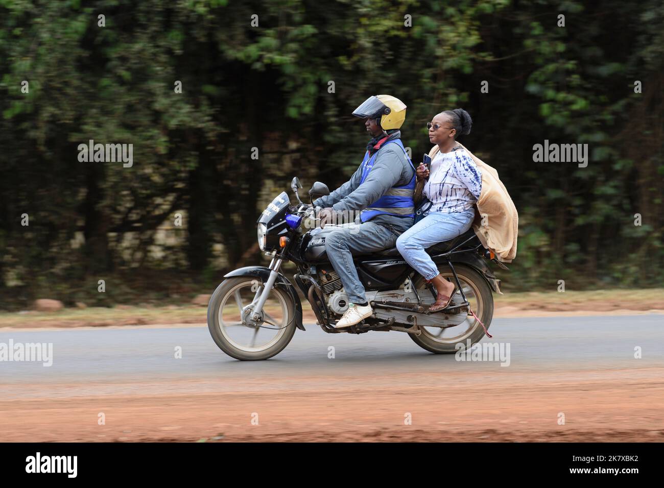 Un passager de pilolion sur des taxis de moto, connu sous le nom de Boda, en Afrique de l'est. Boda bodas sont une partie importante du réseau de transport, étant utilisé Banque D'Images