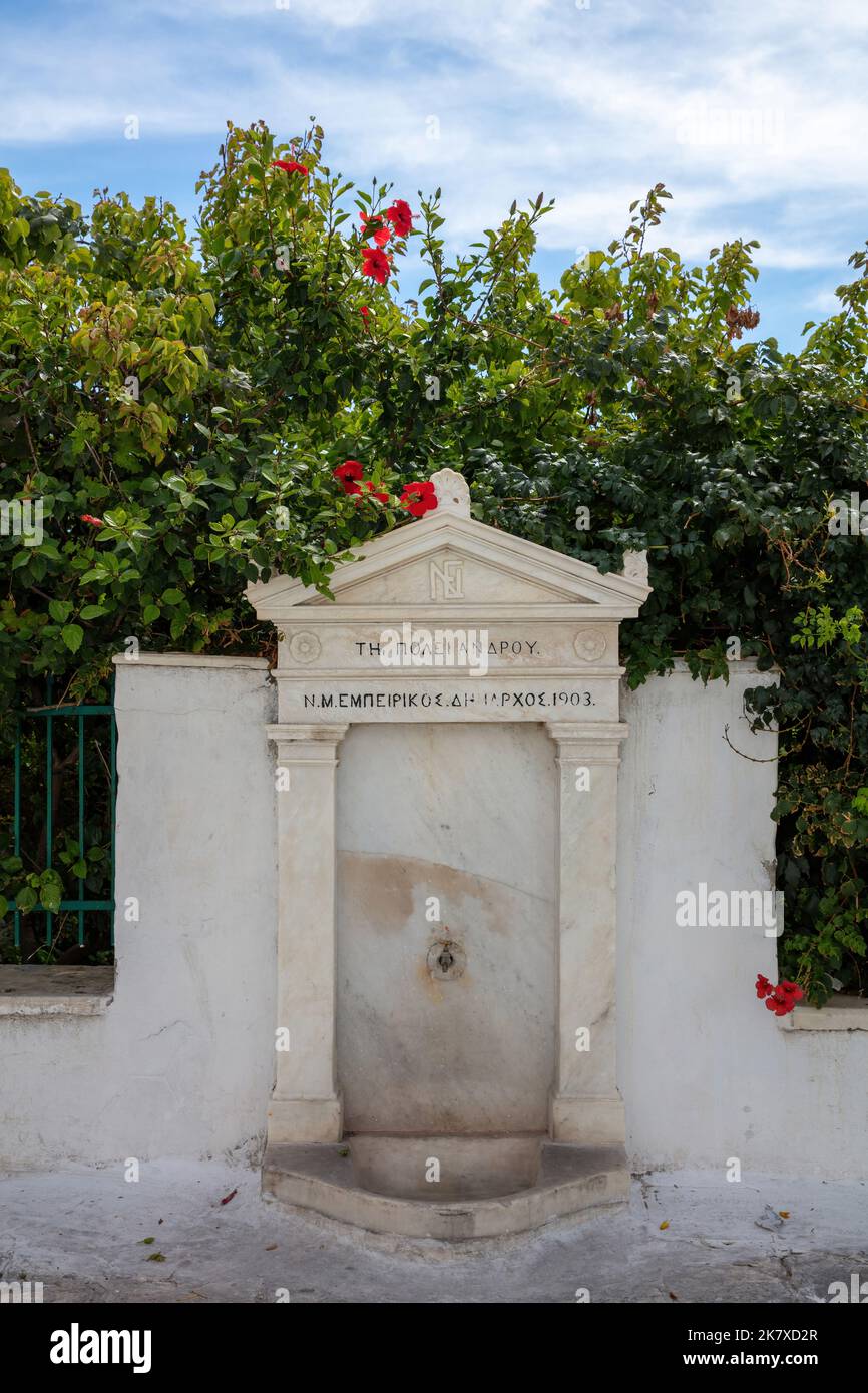Grèce Ile d'Andros, ville de Chora, Cyclades. Robinet de rue néoclassique en marbre, cadeau de l'ancien maire avec l'aqueduc, usine d'hibiscus. Verticale Banque D'Images