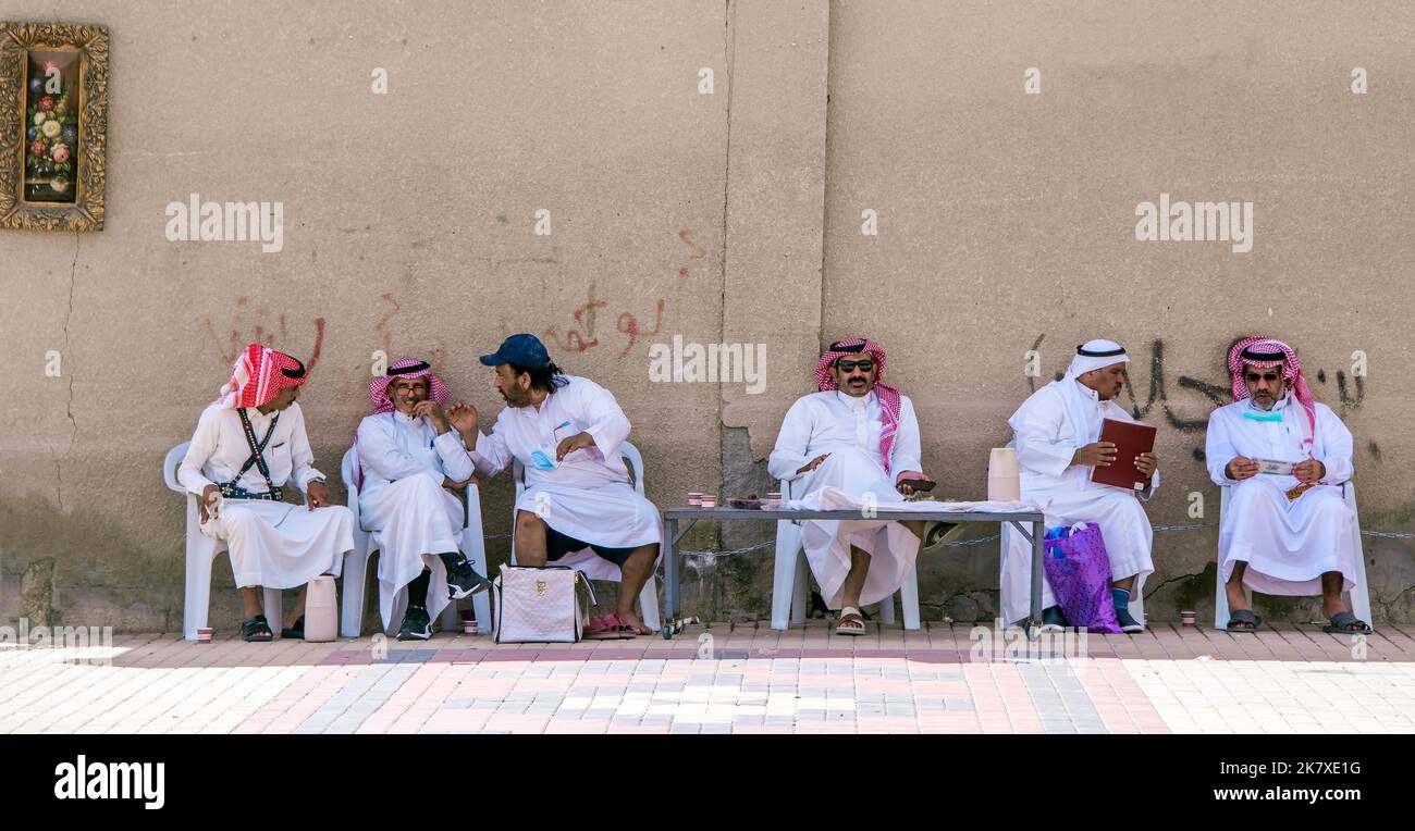 Groupe d'hommes portant des vêtements traditionnels assis contre un mur Riyad Arabie Saoudite Banque D'Images