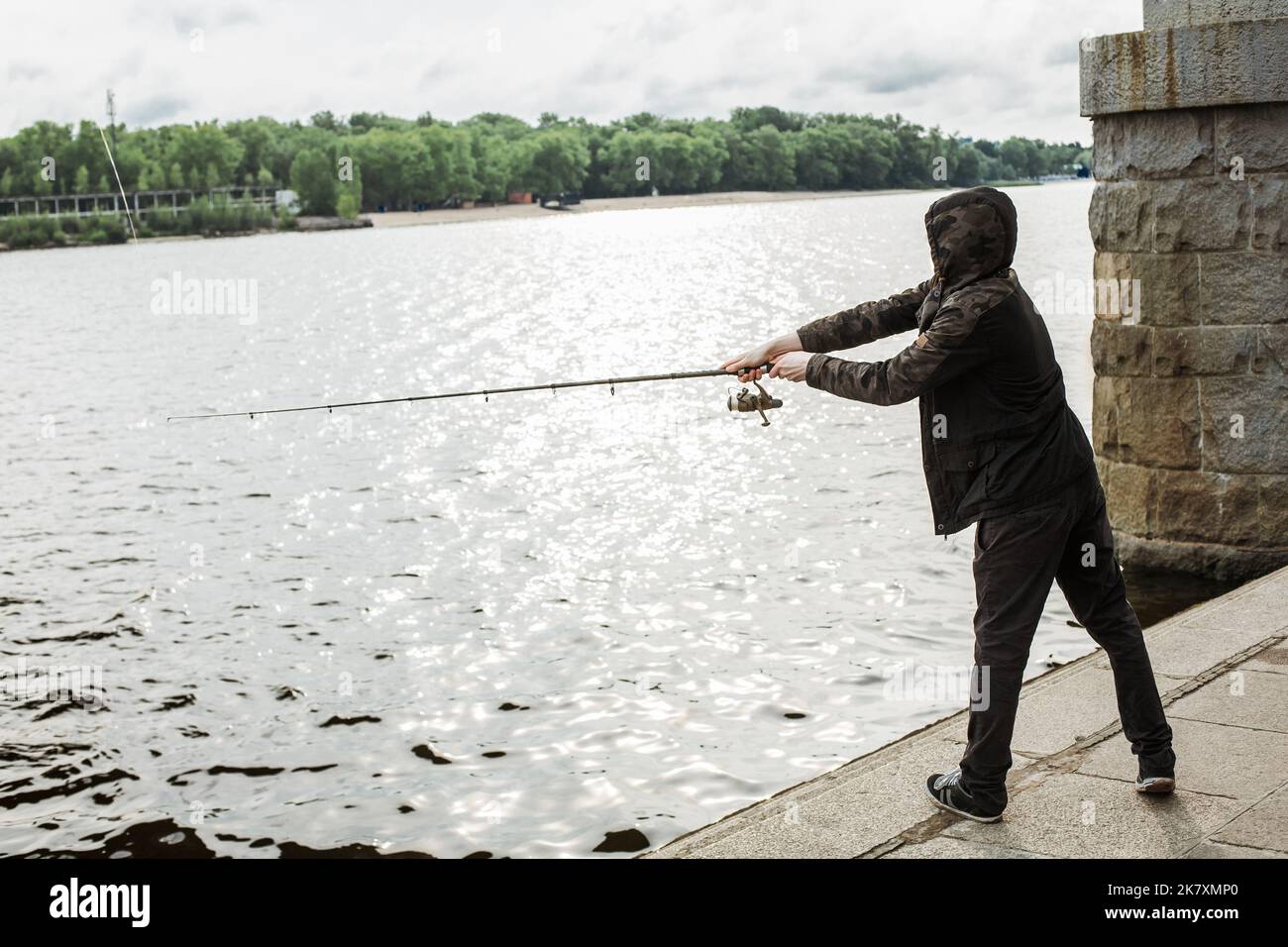 Un jeune homme pêche avec un spinning sur la rivière Banque D'Images