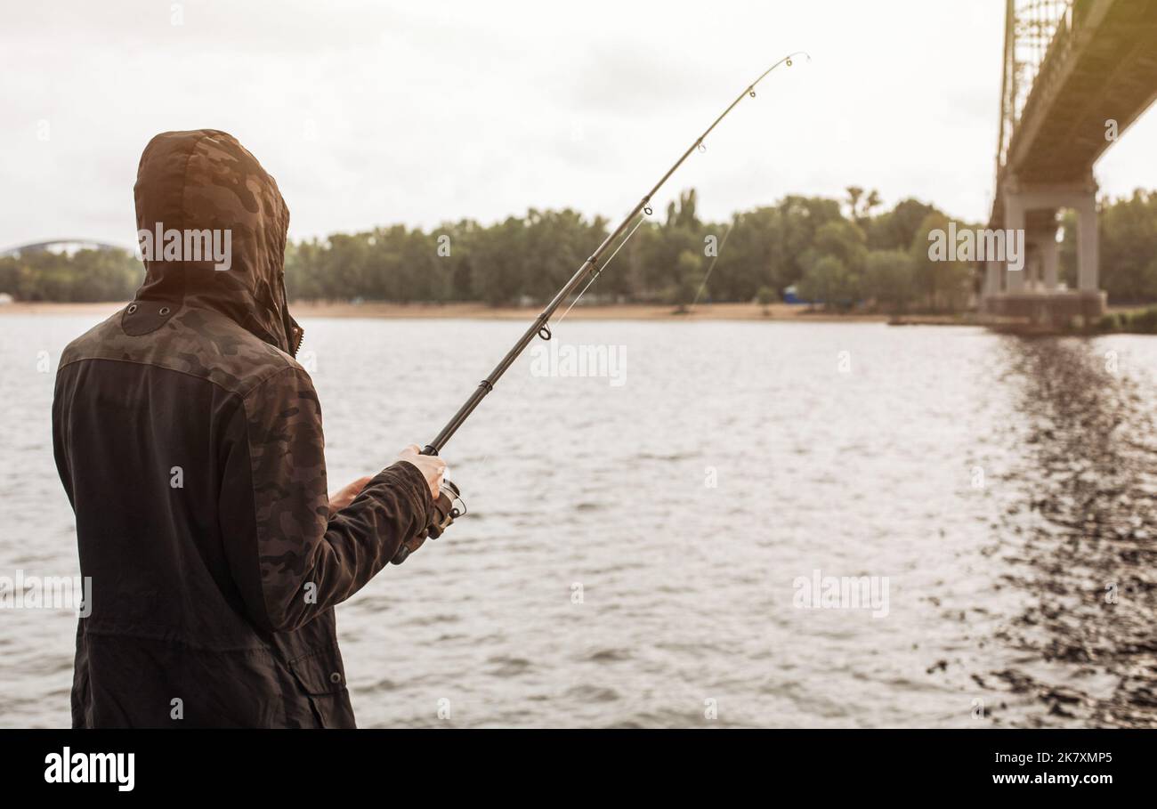 Un jeune homme pêche avec un spinning sur la rivière Banque D'Images