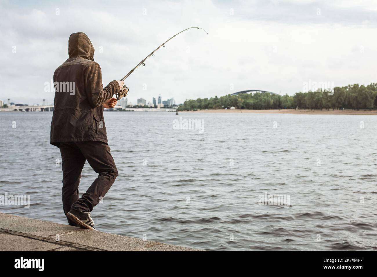 Un jeune homme pêche avec un spinning sur la rivière Banque D'Images