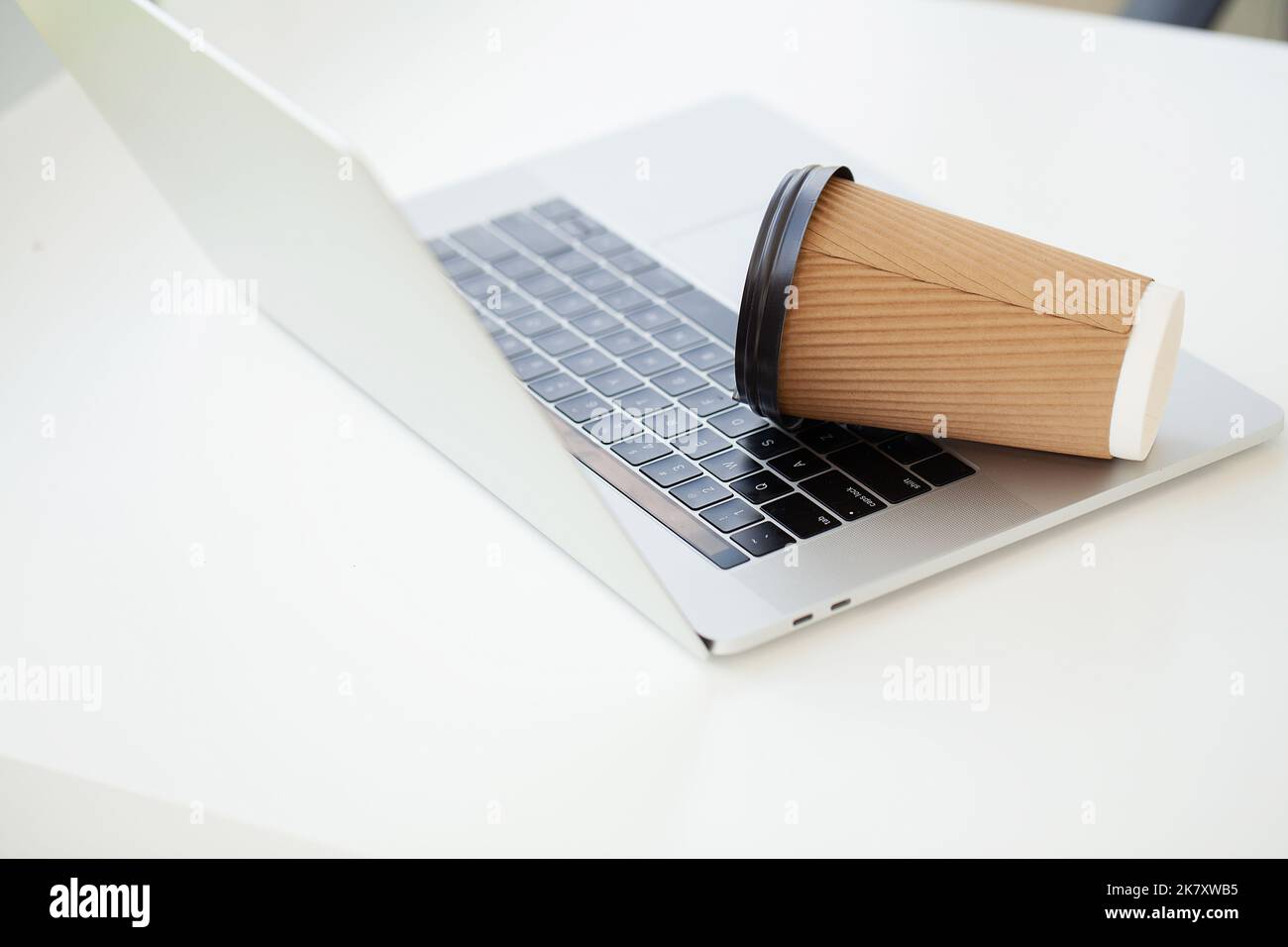 Versez du café sur le clavier de l'ordinateur portable à partir du verre de papier Banque D'Images Versez du café sur le clavier de l'ordinateur portable à partir du verre de papier Banque D'Images