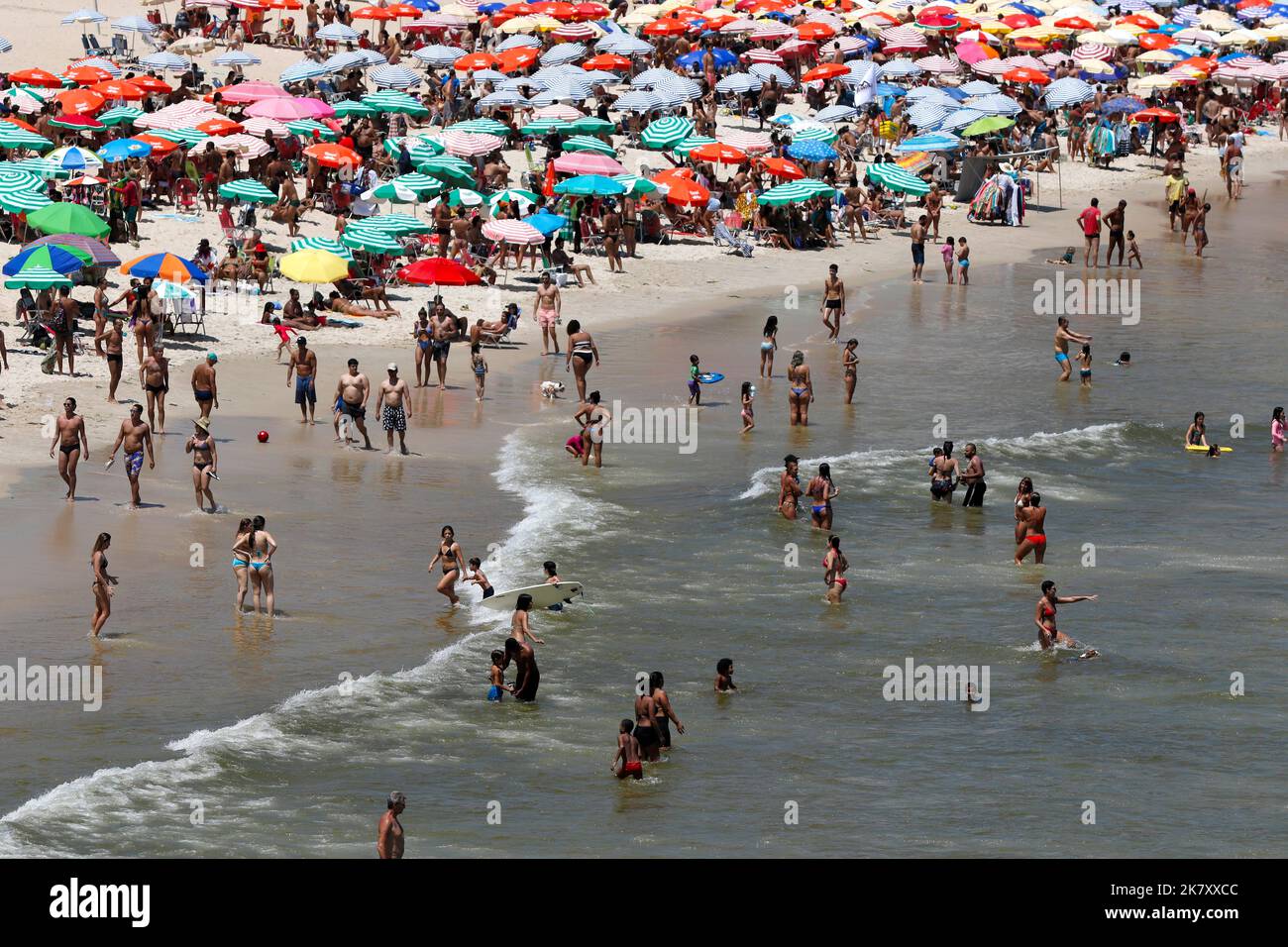 Plage de Leblon, Rio de Janeiro, Brésil. Les gens se bronzent près de la rive avec des parasols colorés. La foule aime nager en mer en été. Voyage tropical Banque D'Images