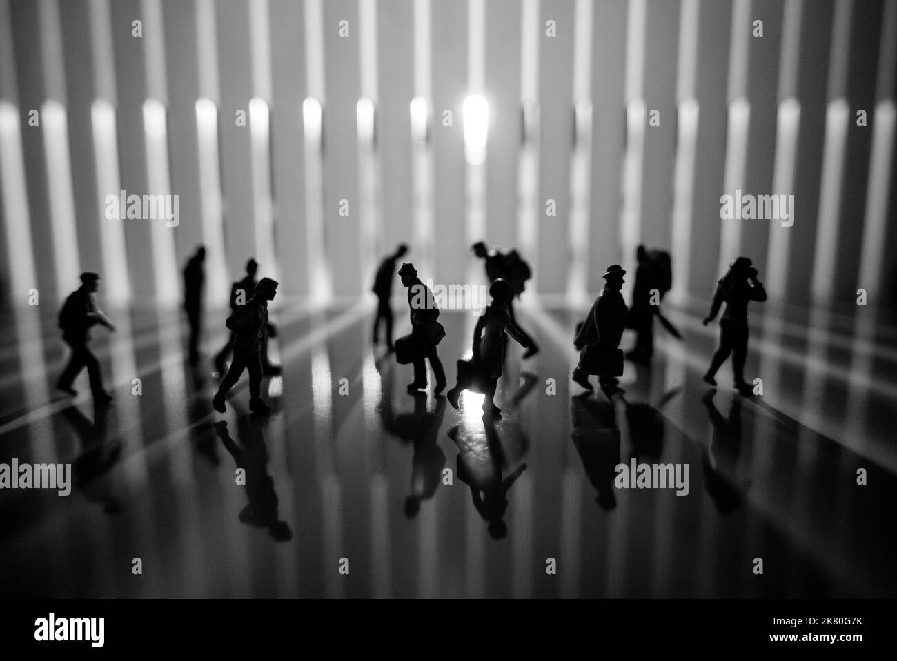 Miniature People Toys studio - vue latérale de l'effet noir et blanc des personnes avec de longues ombres qui marchent au lever ou au coucher du soleil dans la rue. Banque D'Images