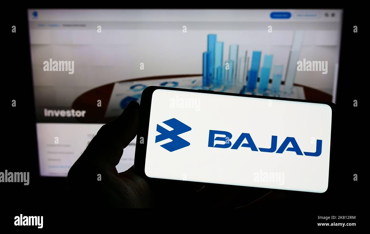 Personne tenant un smartphone avec le logo de la compagnie automobile indienne Bajaj Auto Limited sur l'écran devant le site Web. Mise au point sur l'affichage du téléphone. Banque D'Images