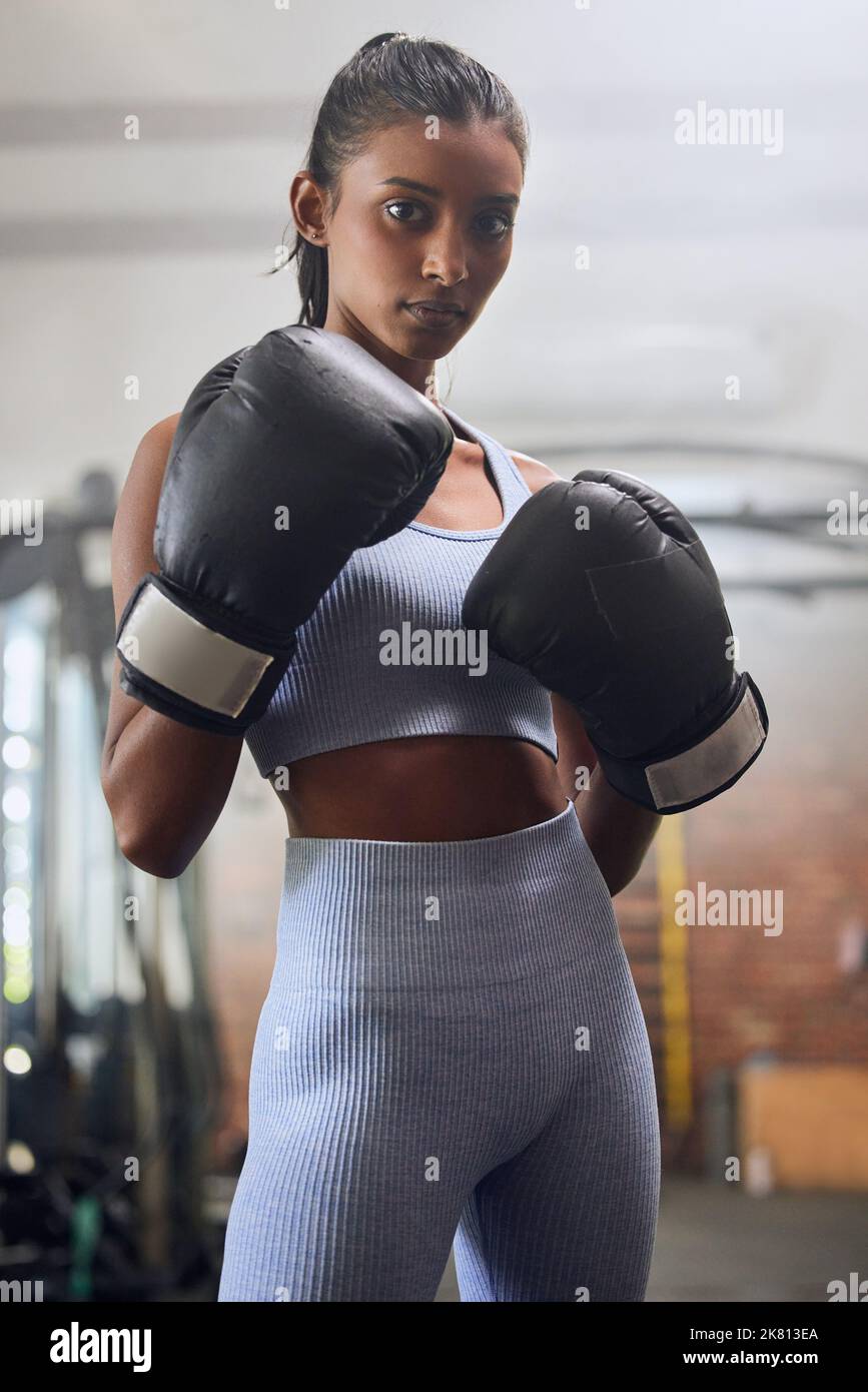 Ne laissez rien vous descendre. Une jeune femme qui passe par une routine d'entraînement de boxe dans une salle de gym. Banque D'Images