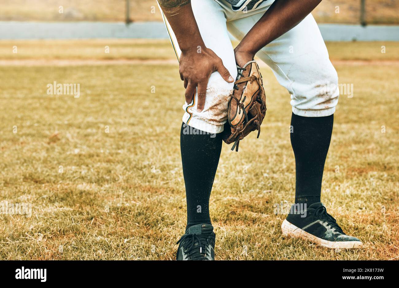 Homme, baseball et sport blessure de jambe souffrant de douleur, agonie et malaise pendant le match d'entraînement ou le match sur le terrain. L'athlète masculin a mal tenu Banque D'Images