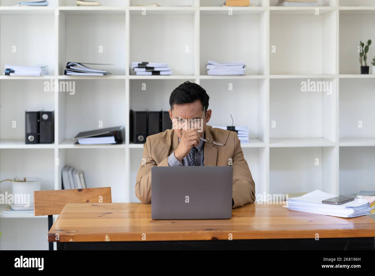 Homme d'affaires asiatique se sentant stressé et frustré lorsqu'il travaille avec un ordinateur portable. Homme entrepreneur en difficulté avec son travail. freelance Banque D'Images