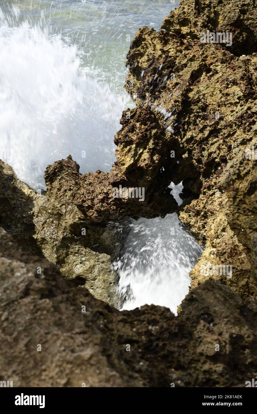 Un gros plan vertical de l'éclaboussure des vagues de l'océan sur des rochers sur une rive Banque D'Images