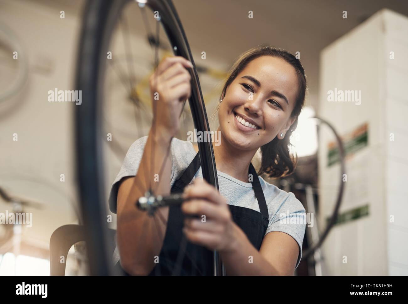 De retour du bleu, rien de nouveau. Portrait d'une jeune femme tenant une roue de vélo au travail. Banque D'Images