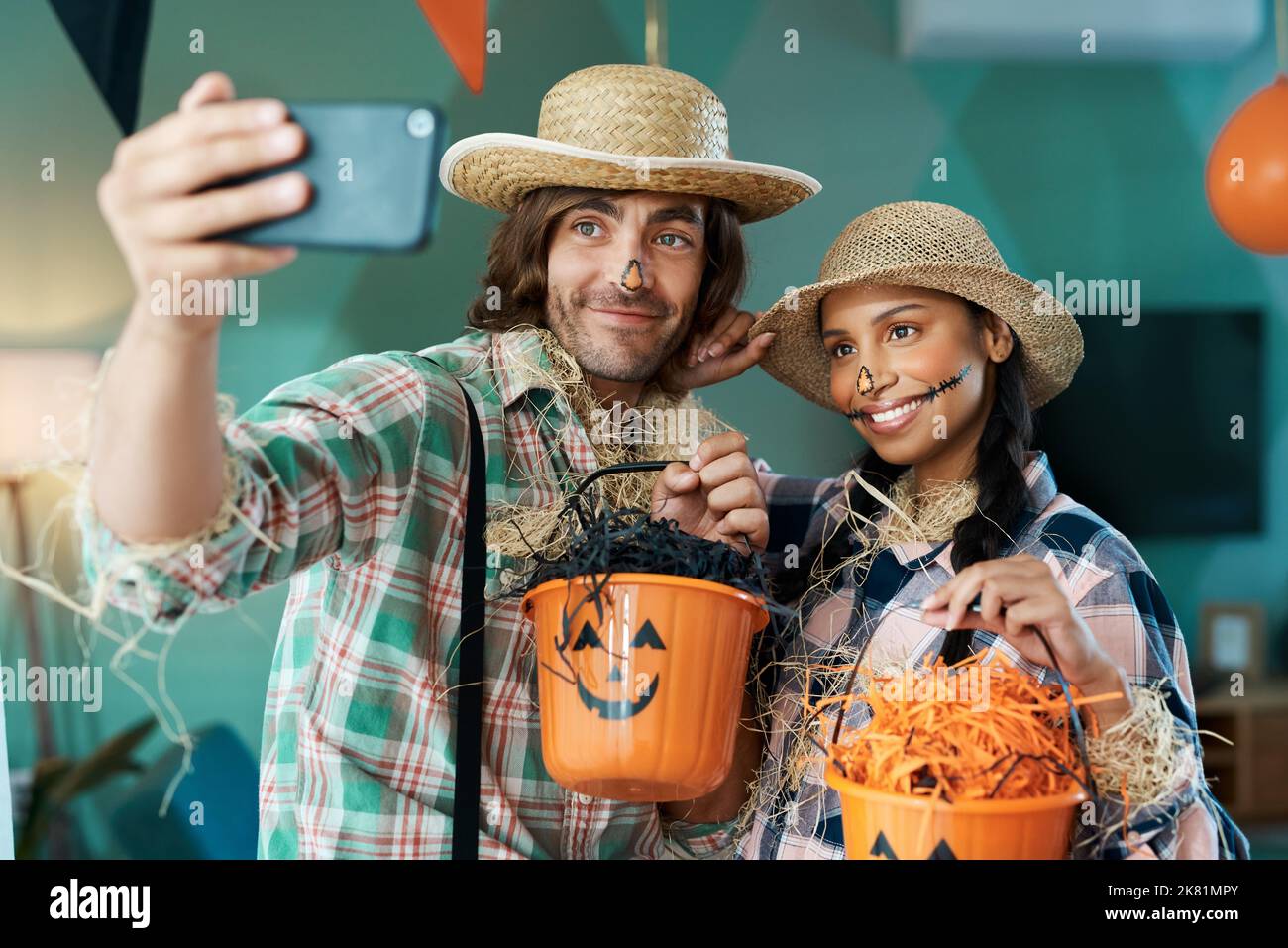 Fêtes d'Halloween. Un jeune couple prend des selfies tout en tenant des seaux à la maison. Banque D'Images